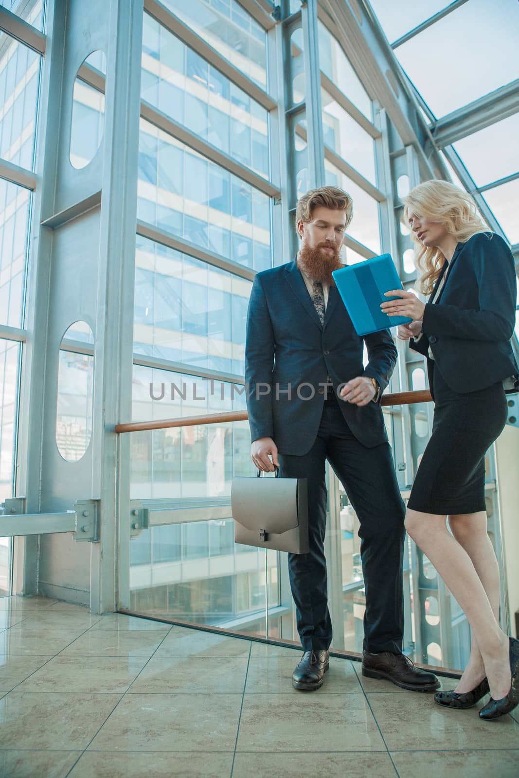 Business partners talking and looking at tablet pc at business center