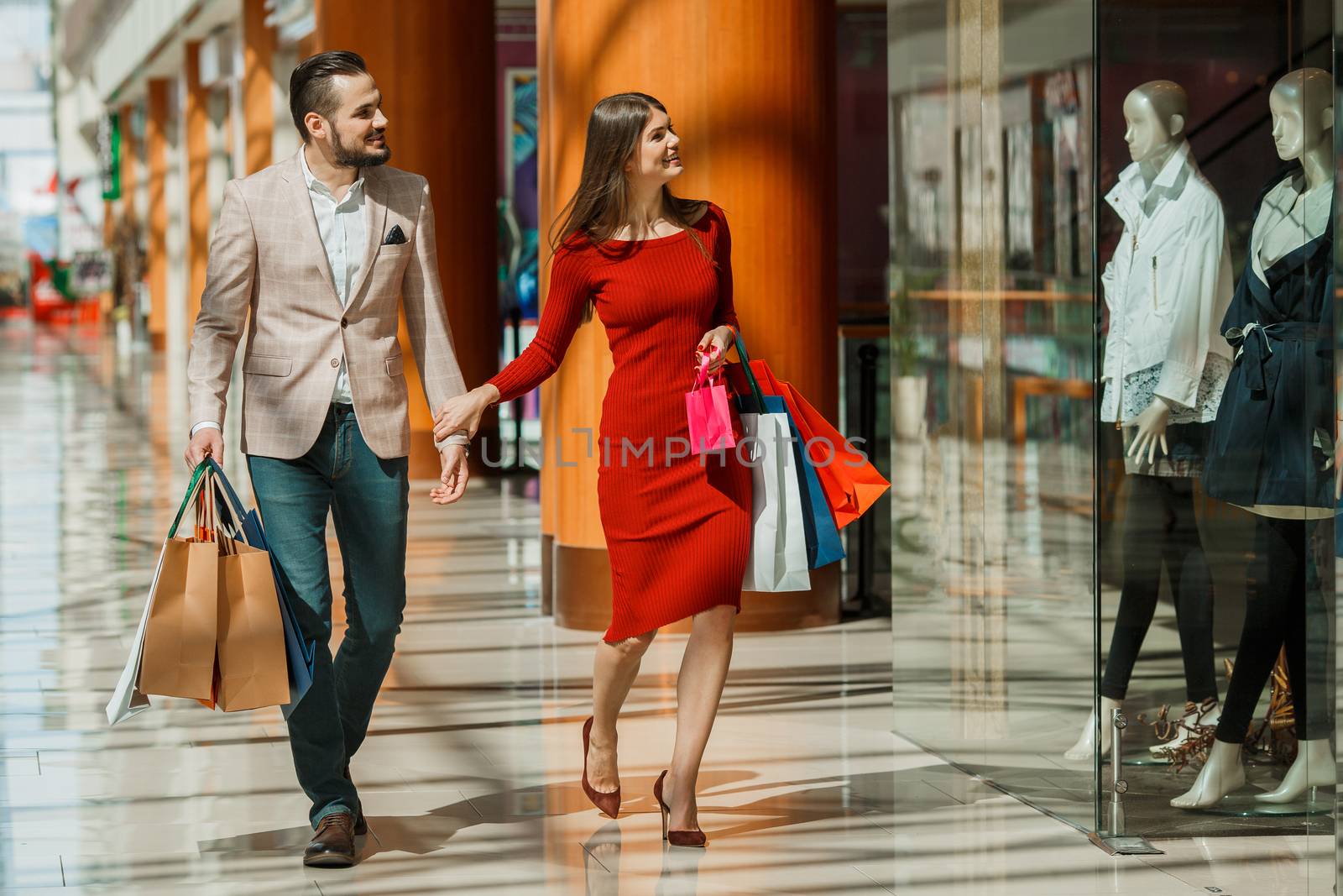 Happy beautiful young couple with shopping bags in mall