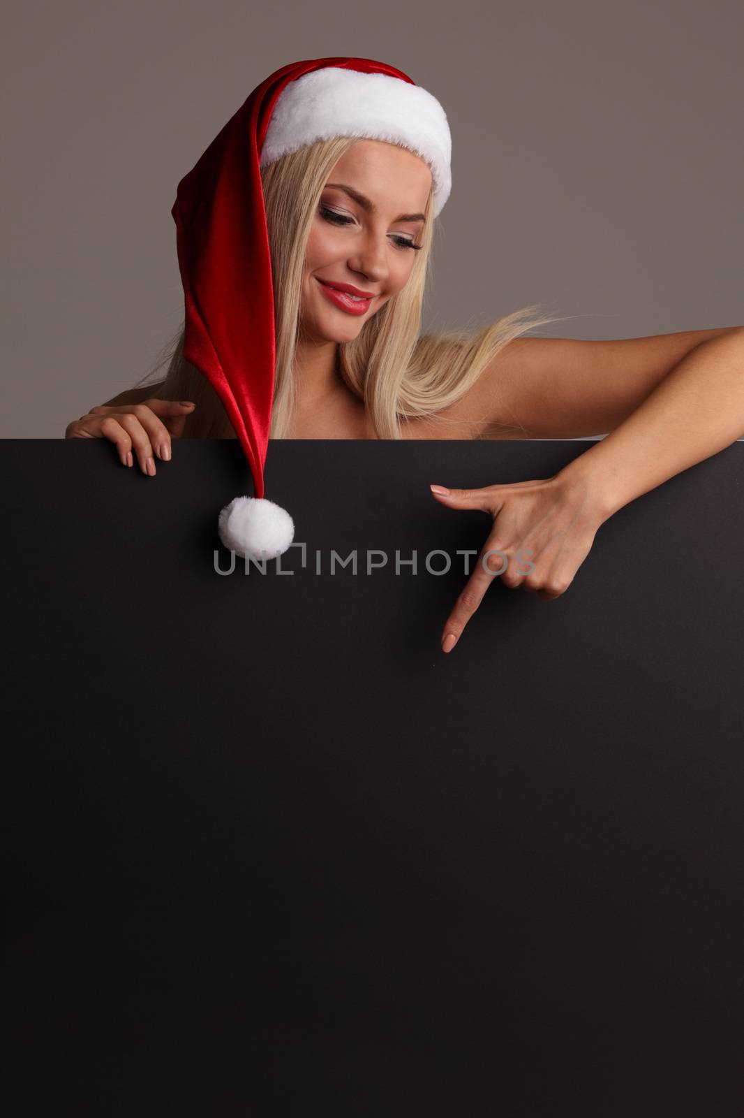 Santa girl holding blank black sign billboard. Christmas woman in Santa hat showing paper sign.