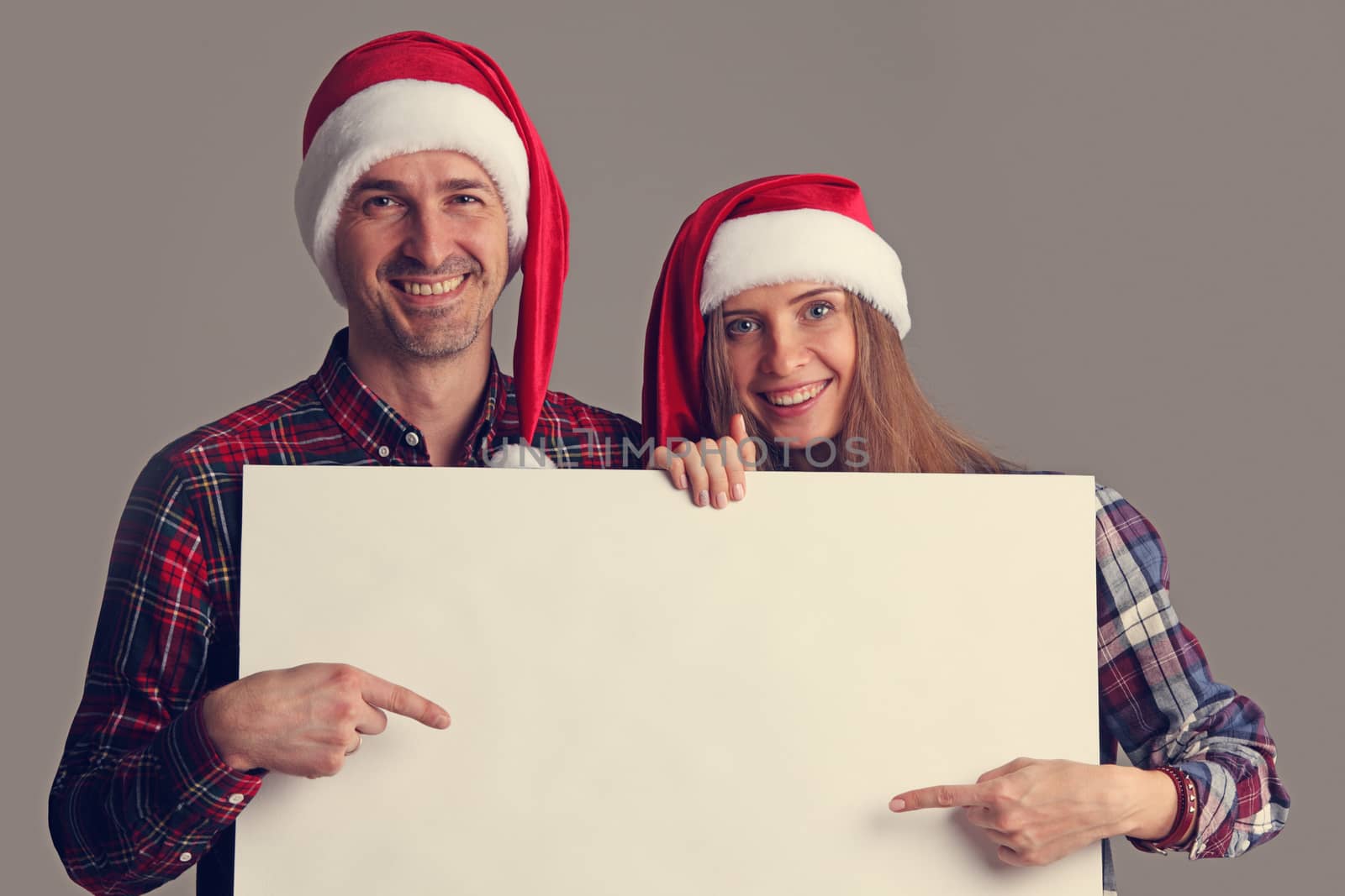 Couple in Santa hats with banner by ALotOfPeople