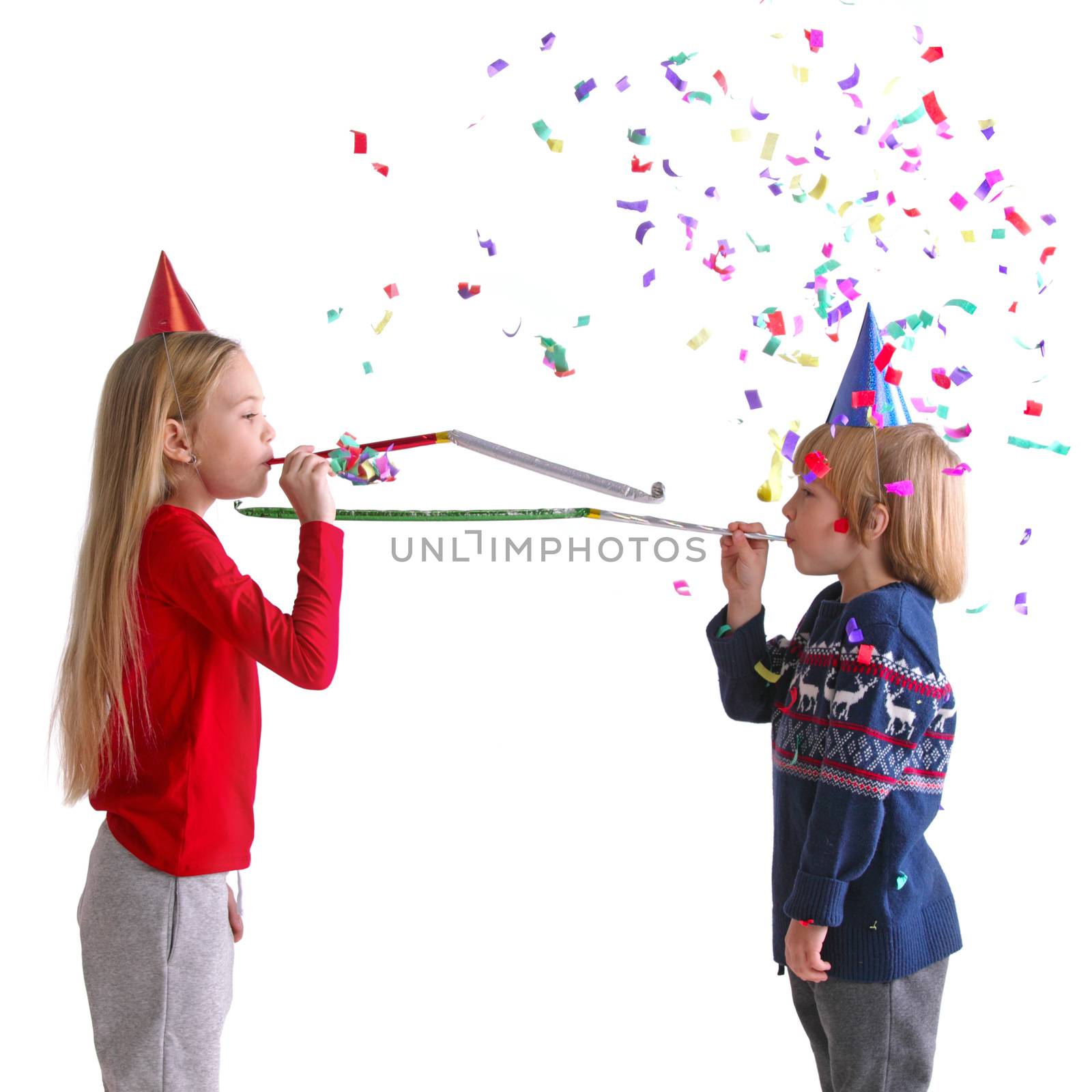 Children blowing party trumpets with confetti celebrating new year