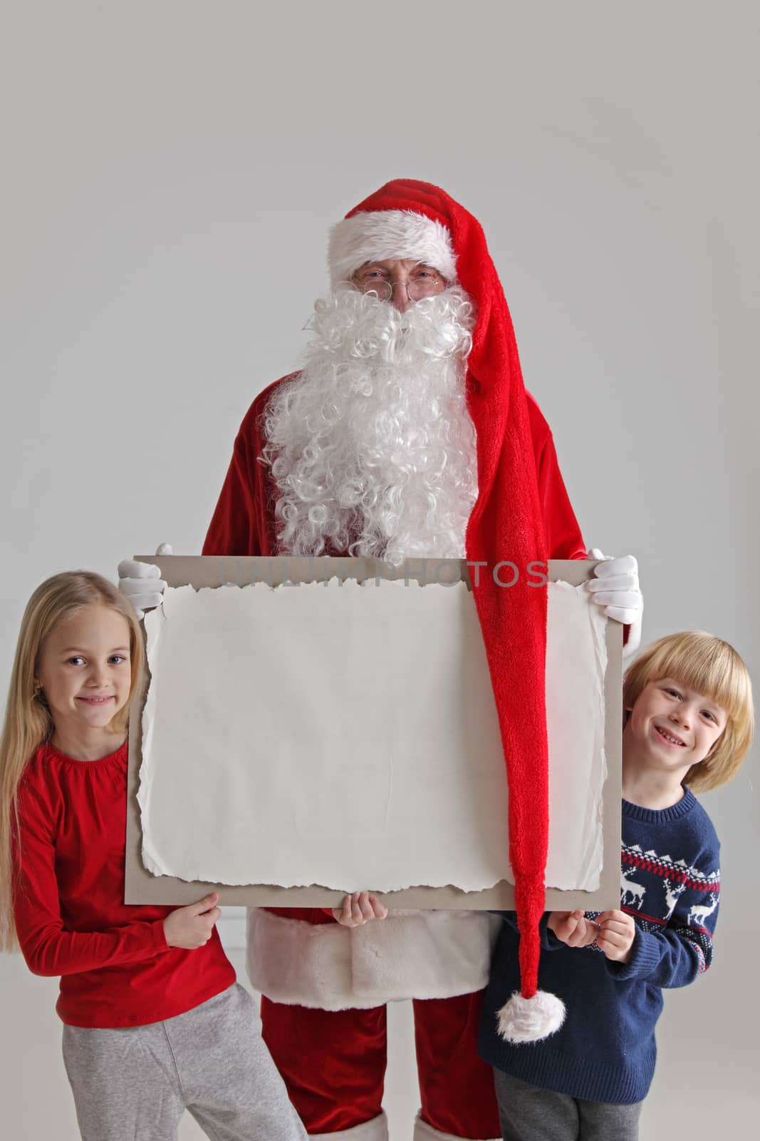 Santa Claus with children holding vintage paper billboard with copy space for text