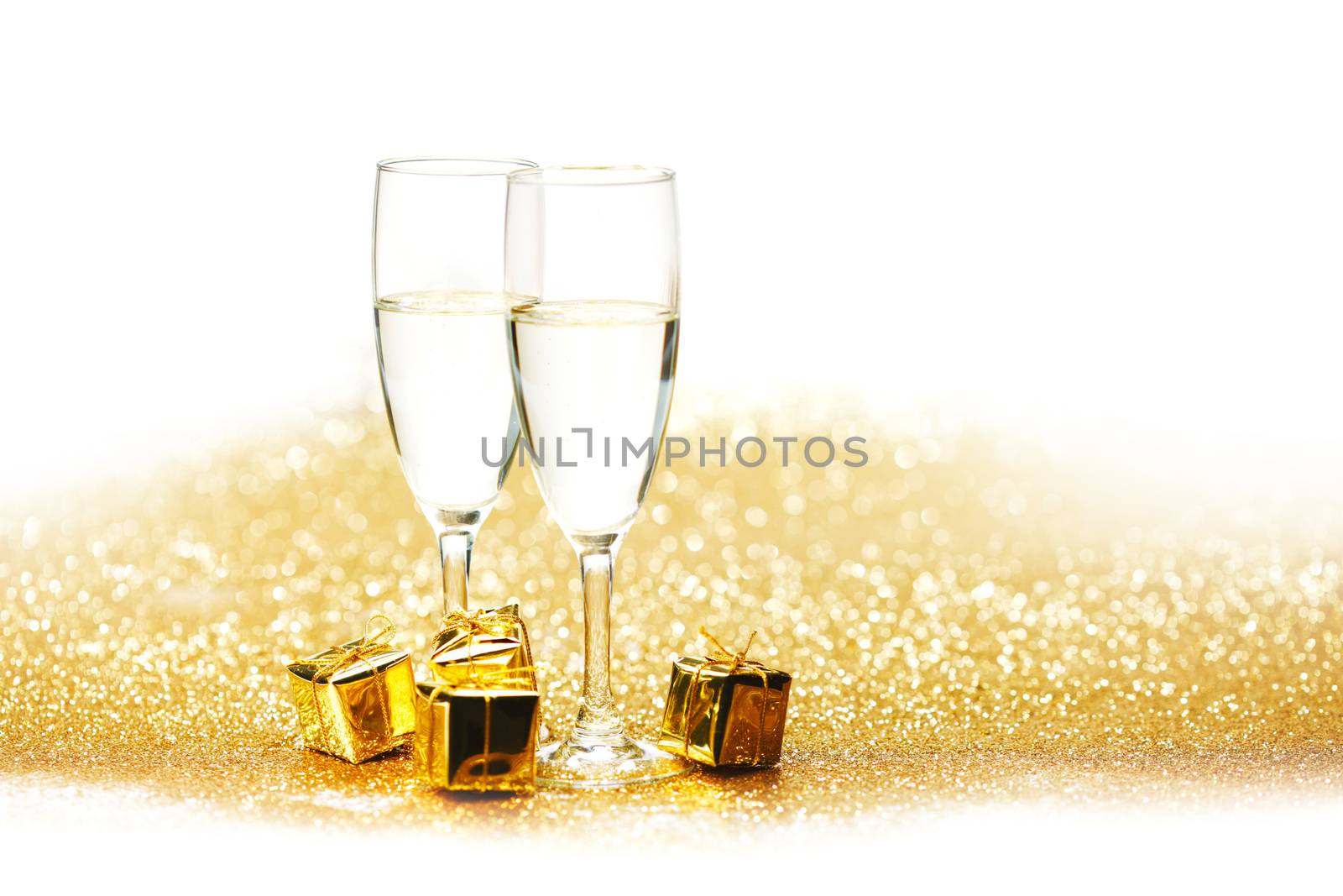 Champagne in glasses and gift box on golden background