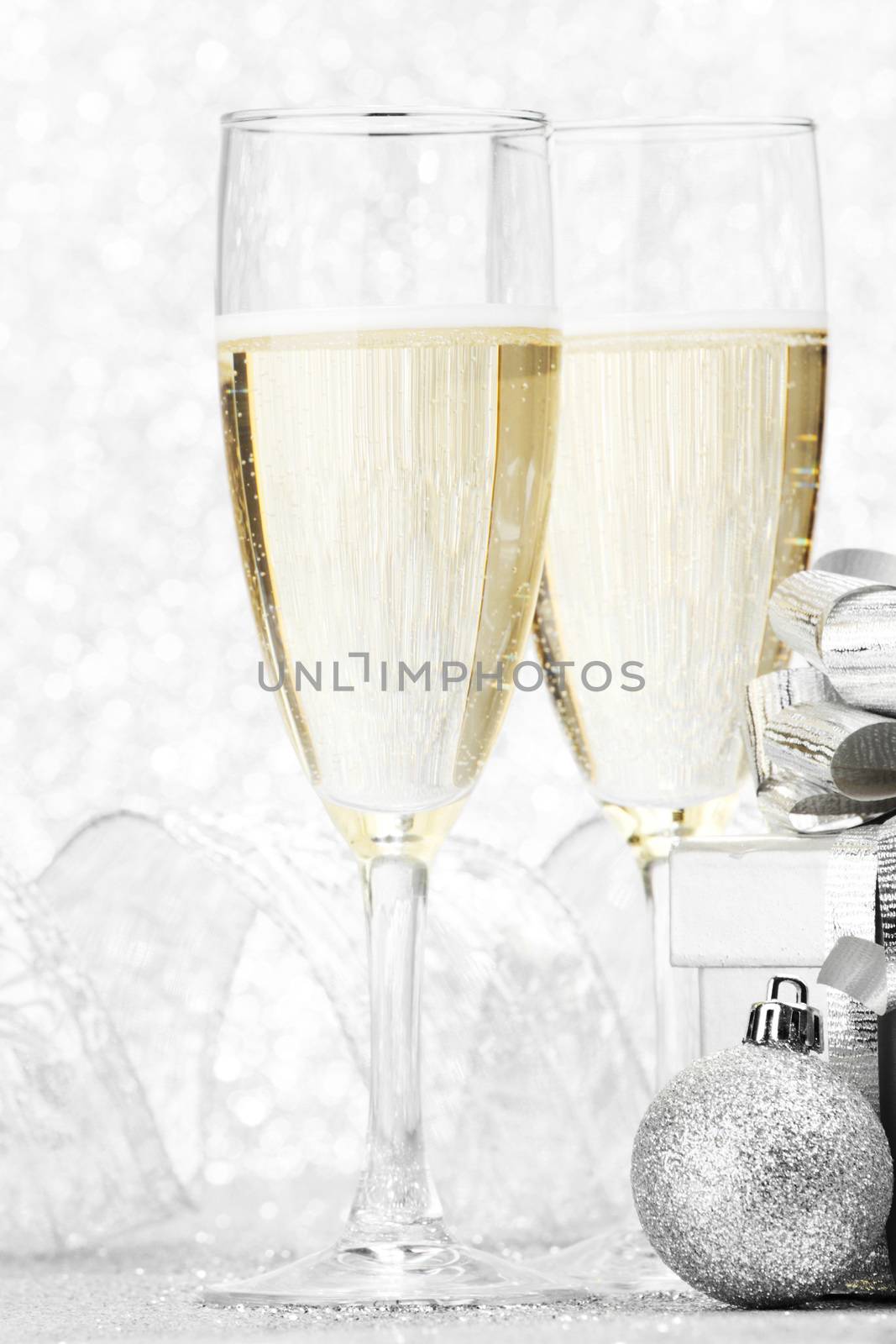 Two champagne glasses and christmas decoration on silver bokeh background