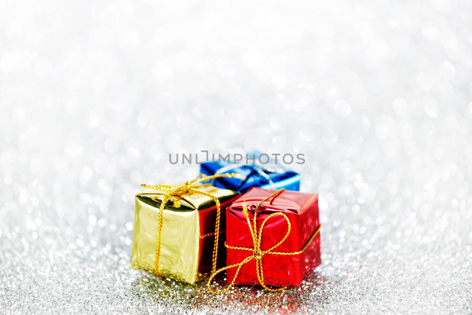 Holiday gifts in colorful boxes on silver bokeh background