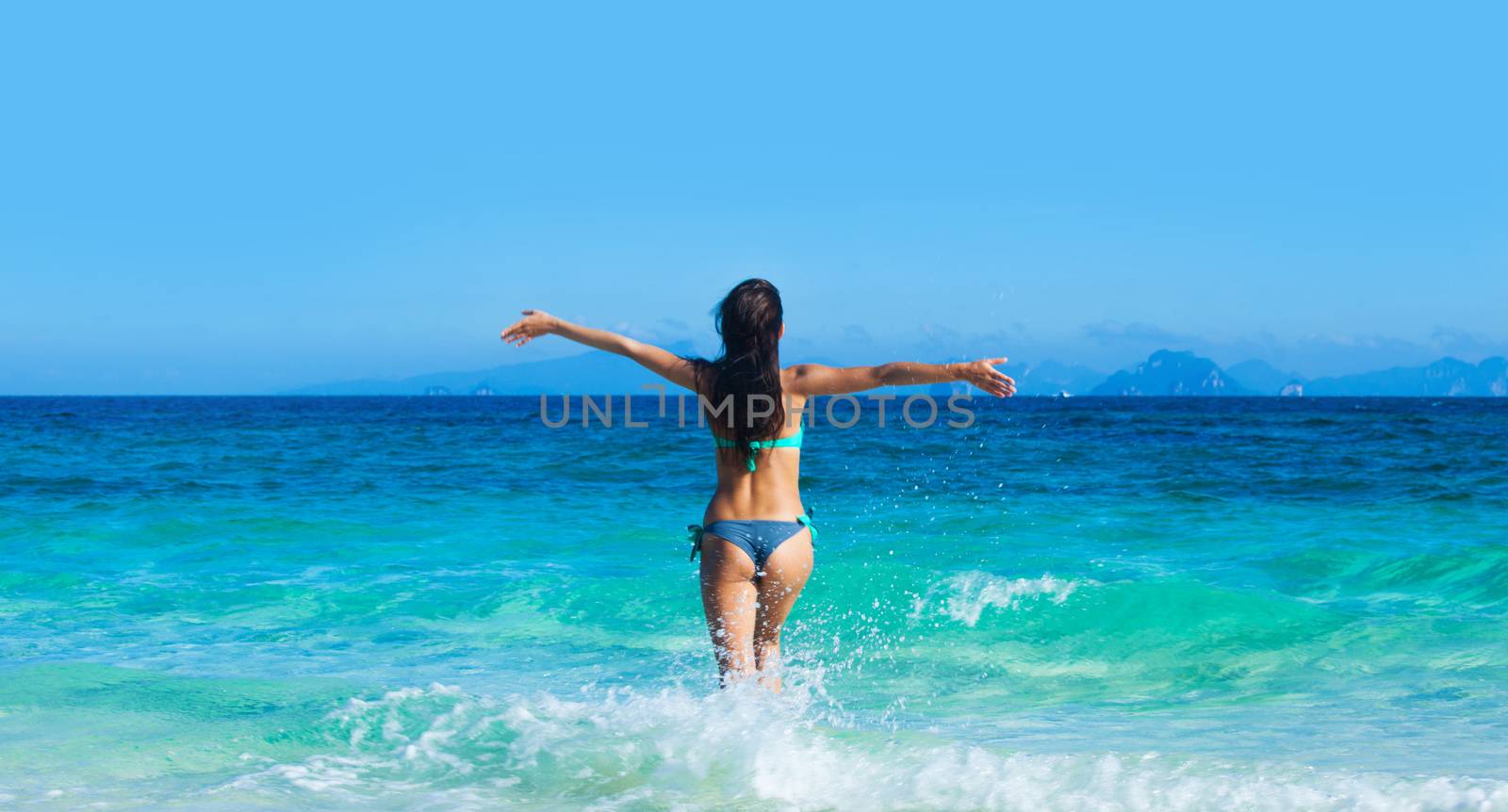 Beautiful woman in bikini run into blue tropical sea