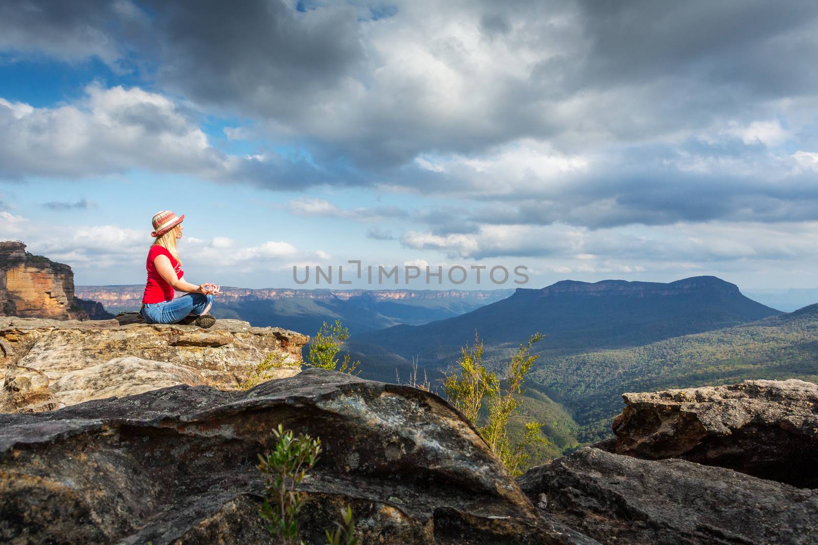 Female finds a quiet spot high in the mountains for some peaceful meditations while gazing across to Mt Solitary