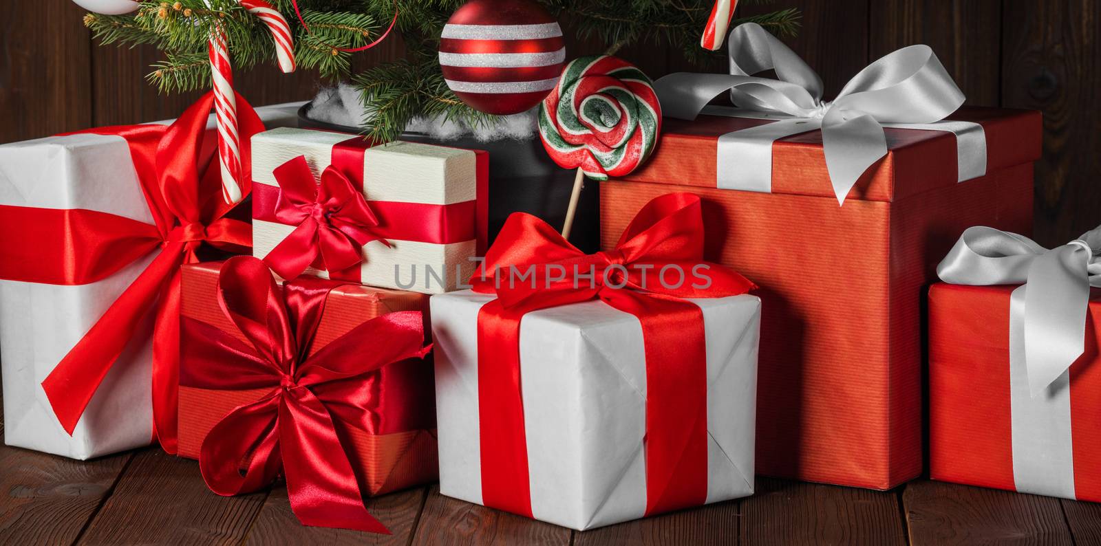 Decorated Christmas gifts under tree with candy canes and striped baubles
