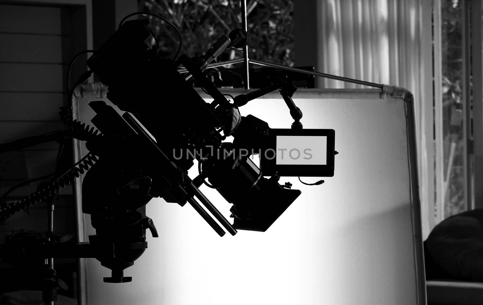 Silhouette images of video camera in tv commercial studio production which operating or shooting by cameraman and film crew team in set and prop on professional crane and tripod for easy to pan tilt or shift