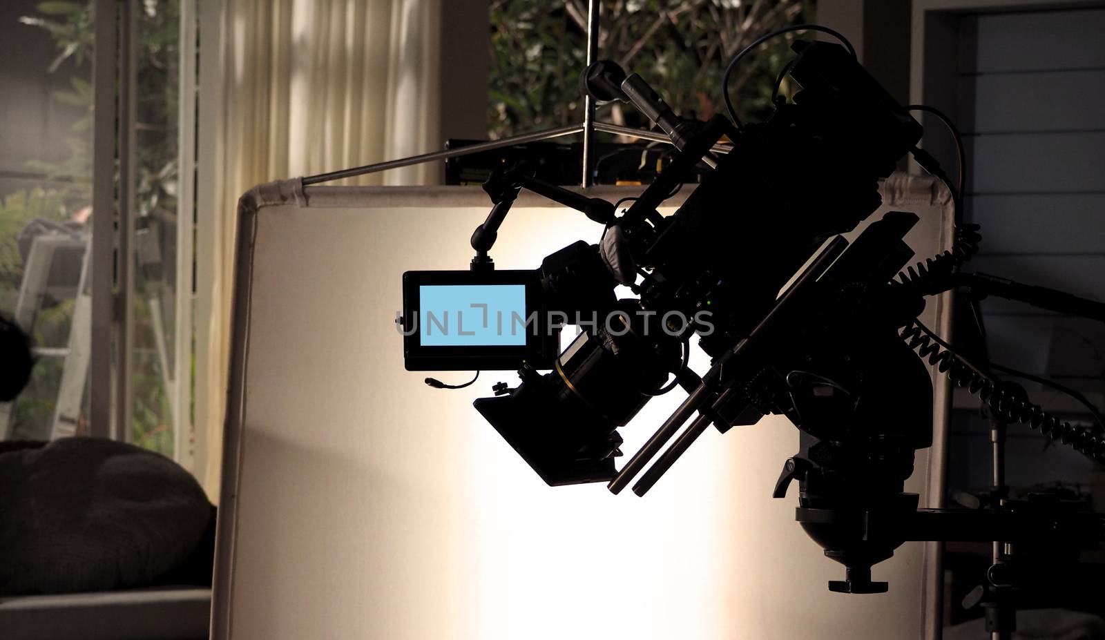 Silhouette images of video camera in tv commercial studio production which operating or shooting by cameraman and film crew team in set and prop on professional crane and tripod for easy to pan tilt or shift