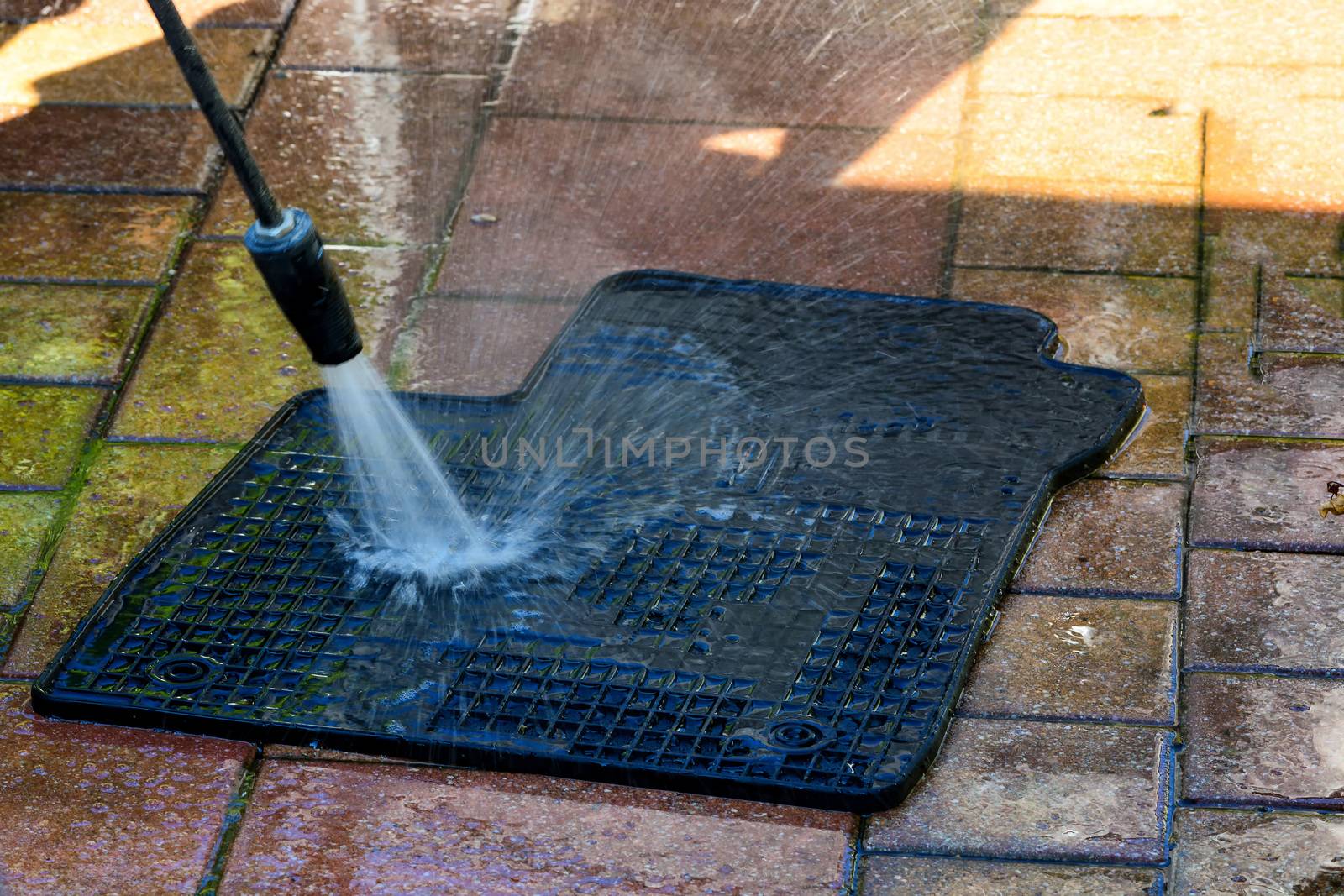 Close up cleaning of car mat with a pressure washer