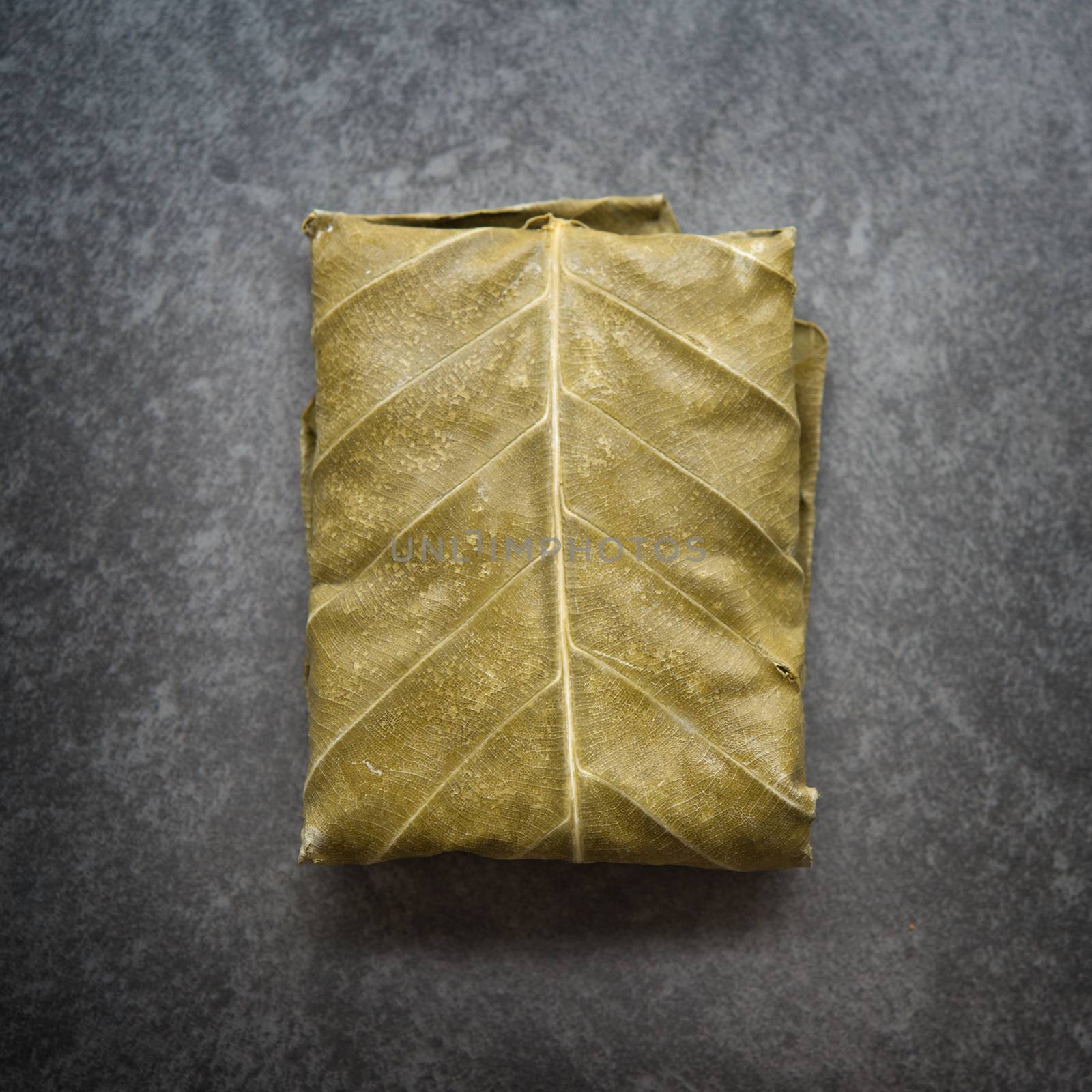 Raw tempeh wrapped in leaf, table top view. by szefei