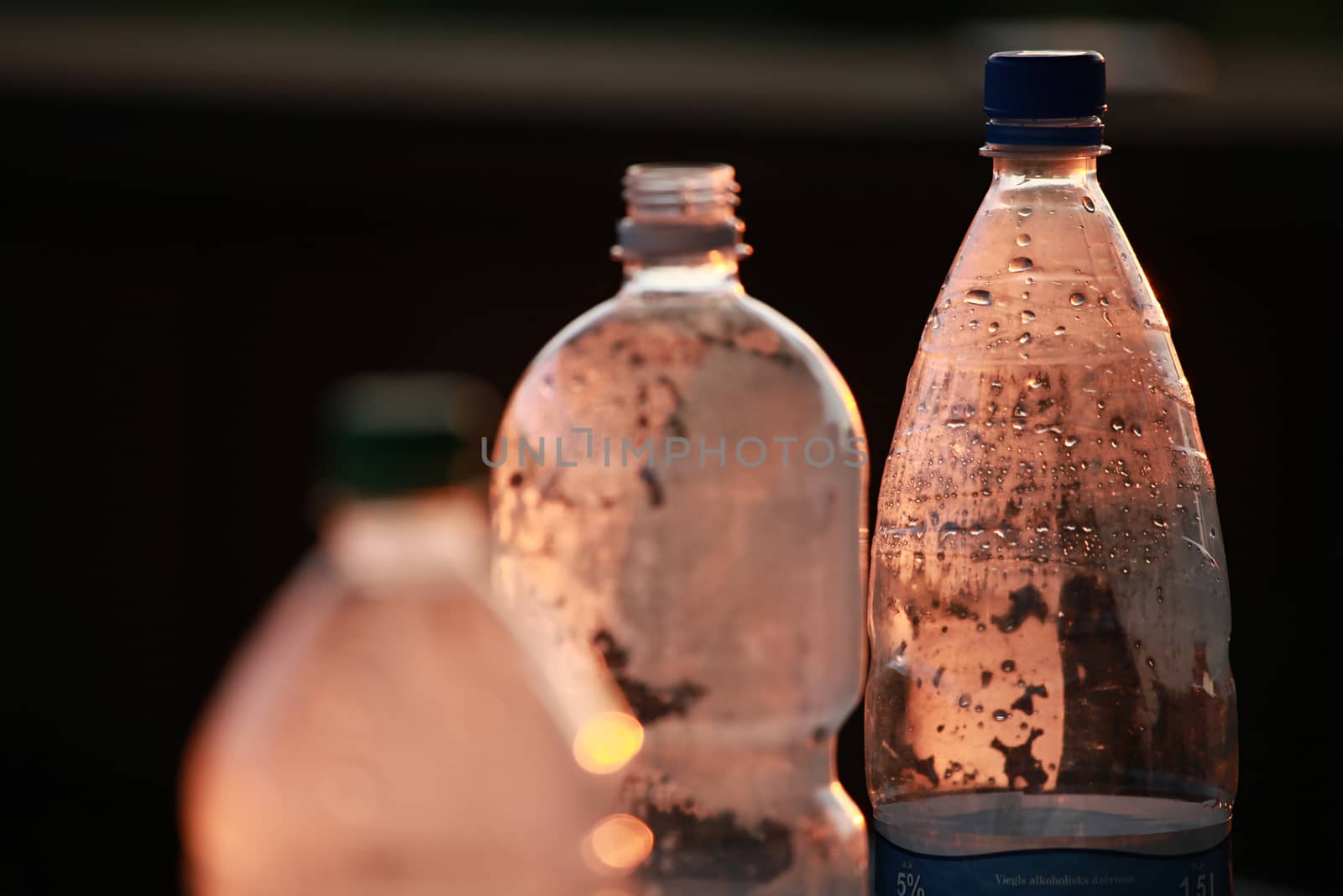 Brown plastic bottles with water drops. Focus on the right bottle.