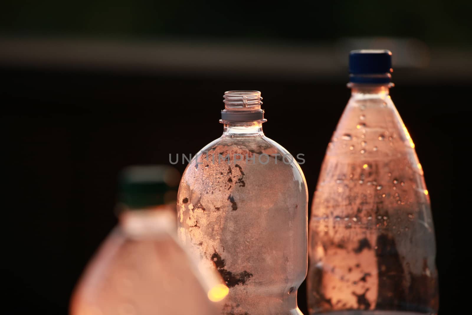 Brown plastic bottles with water drops. Focus on the average bottle.