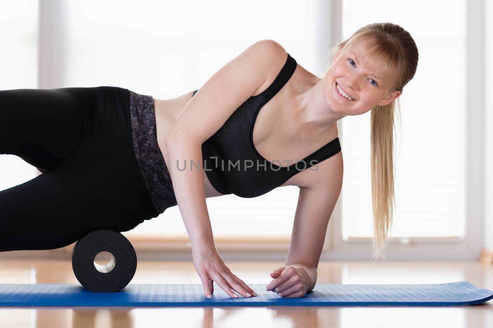 Young girl doing sport excercise with fascia roll