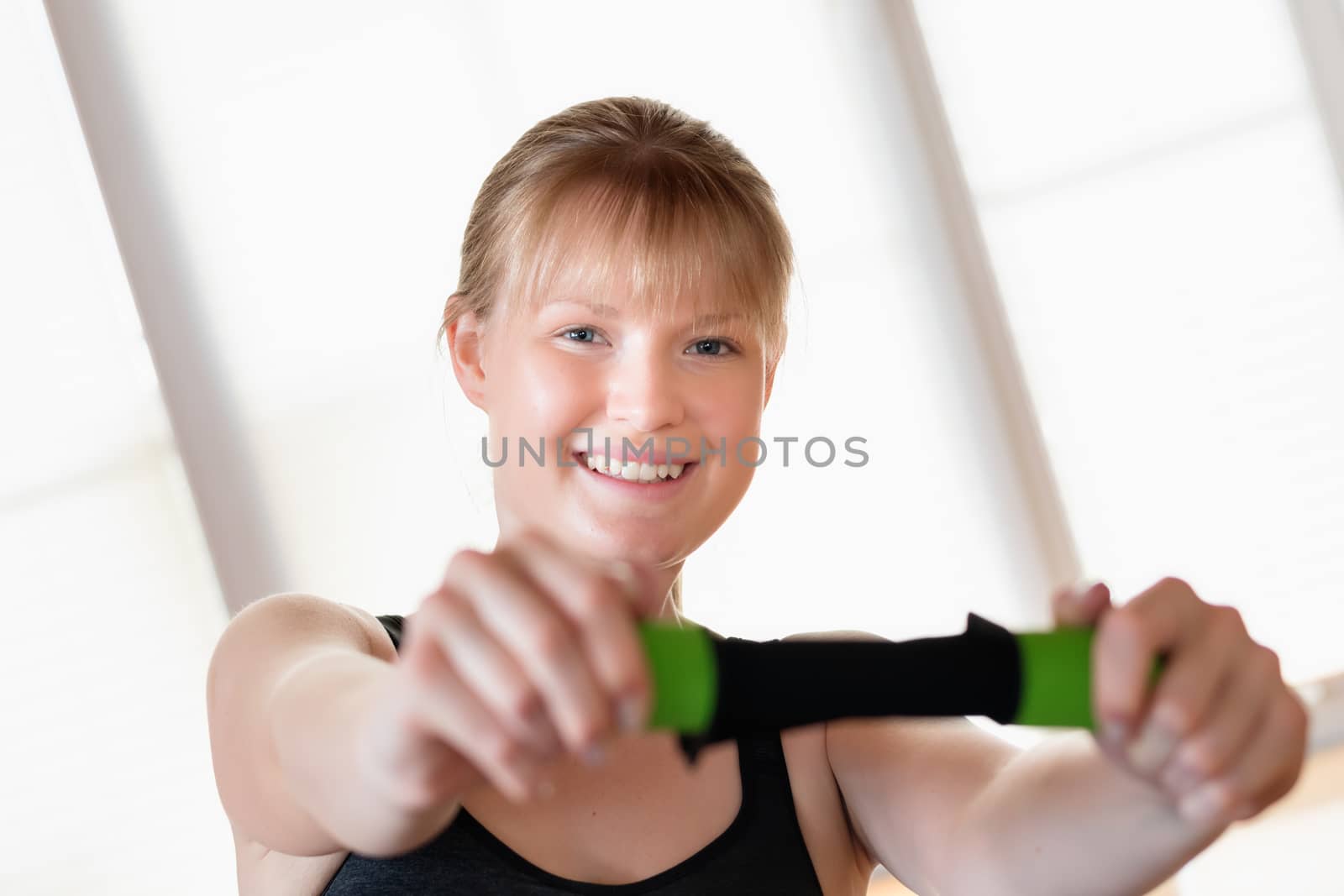 Happy young girl doing crunch exercises with a dumbbell