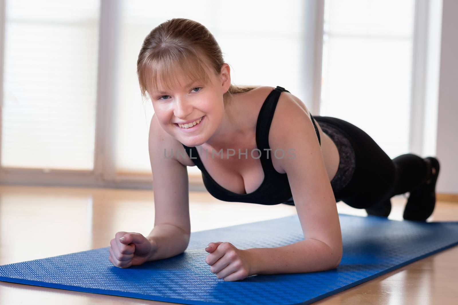 Happy young girl doing plank exercises on the floor at home