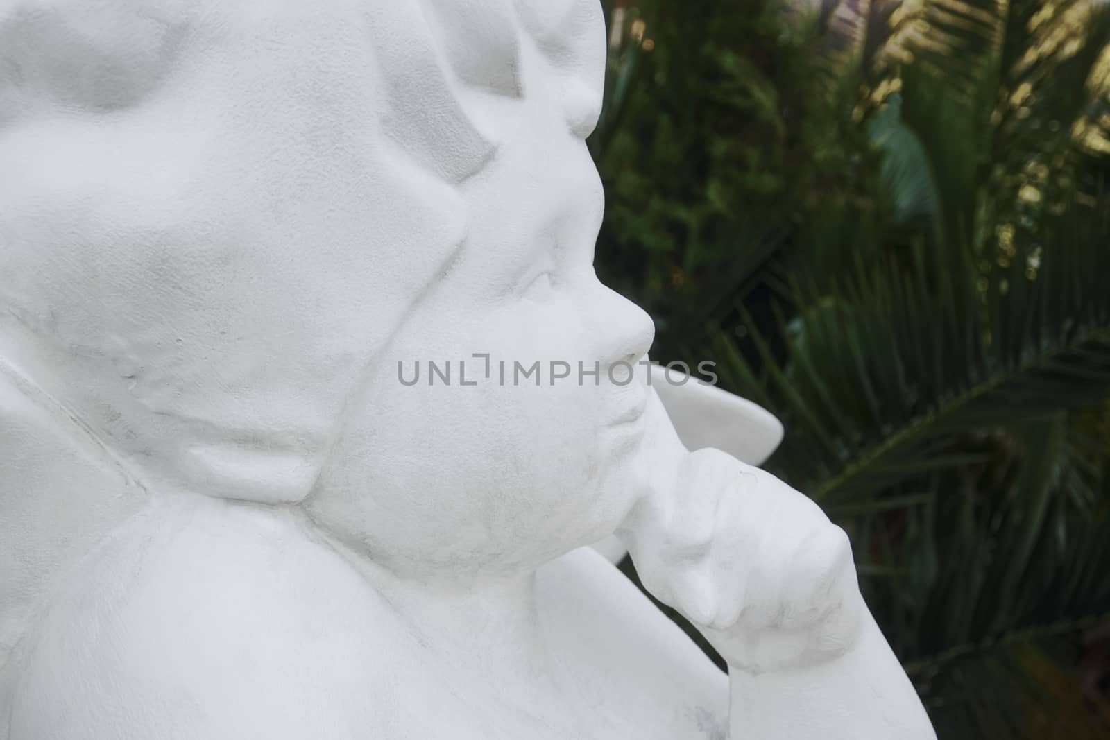 White statue of the angel against the background of palm trees