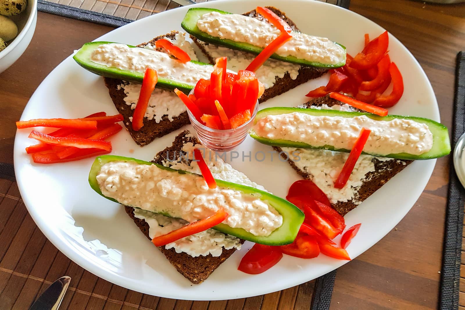 Cucumber cut in half with fresh quark and pepper strips stuffed on black bread. A low-calorie meal and vegan entree