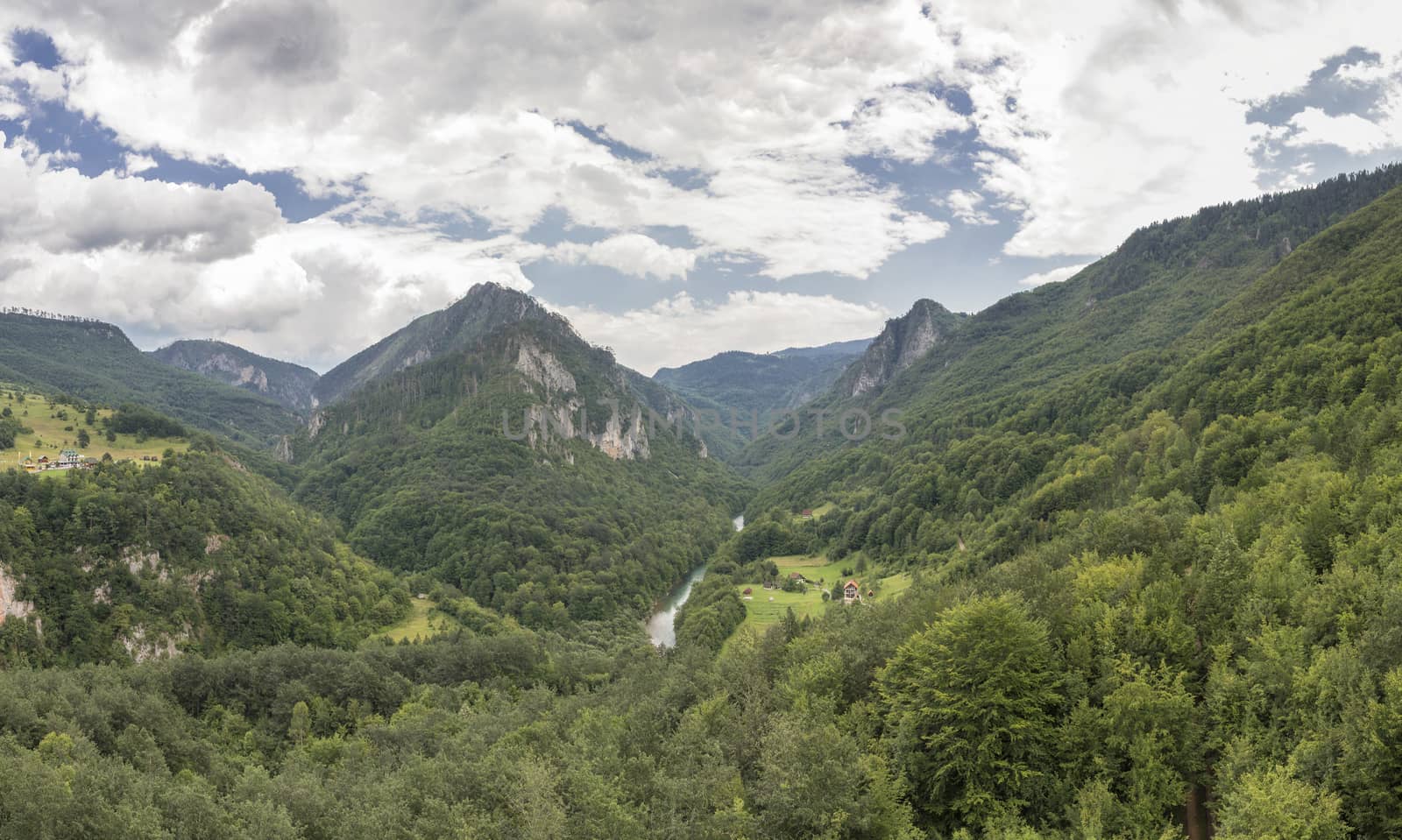 Mountain range and small village houses in green forest near Tara river canyon, view from Djurdjevica Tara Bridge, Montenegro