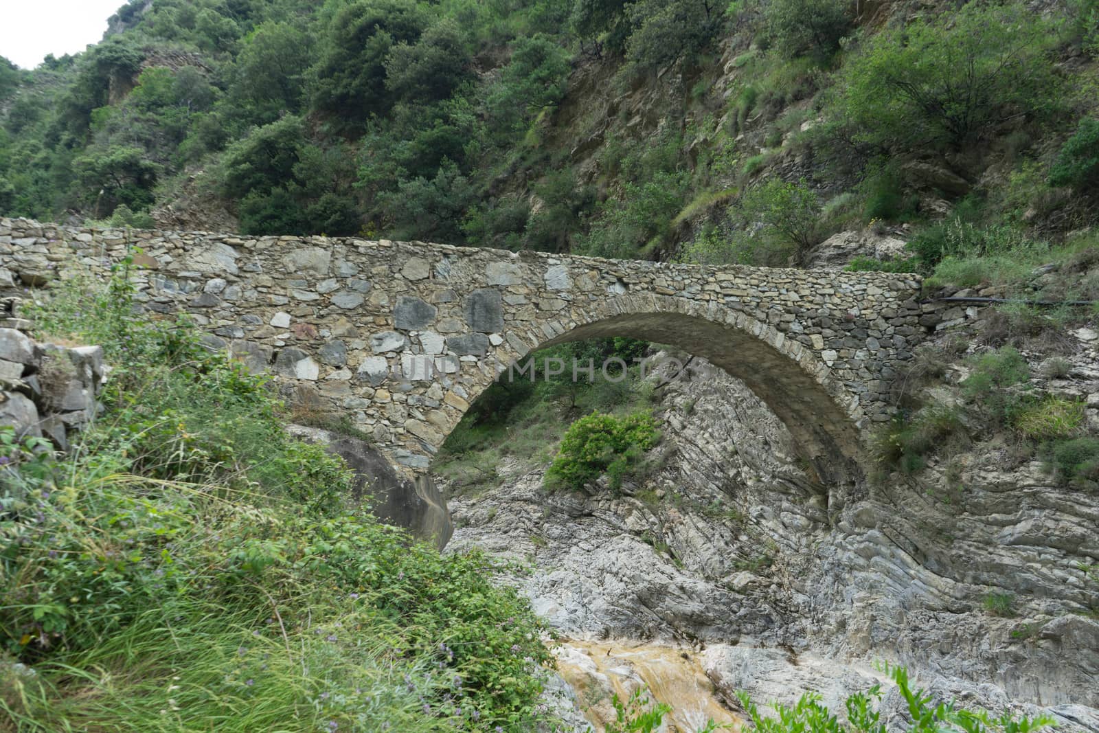 Stone bridge in mountains in the Nervia Valley by cosca