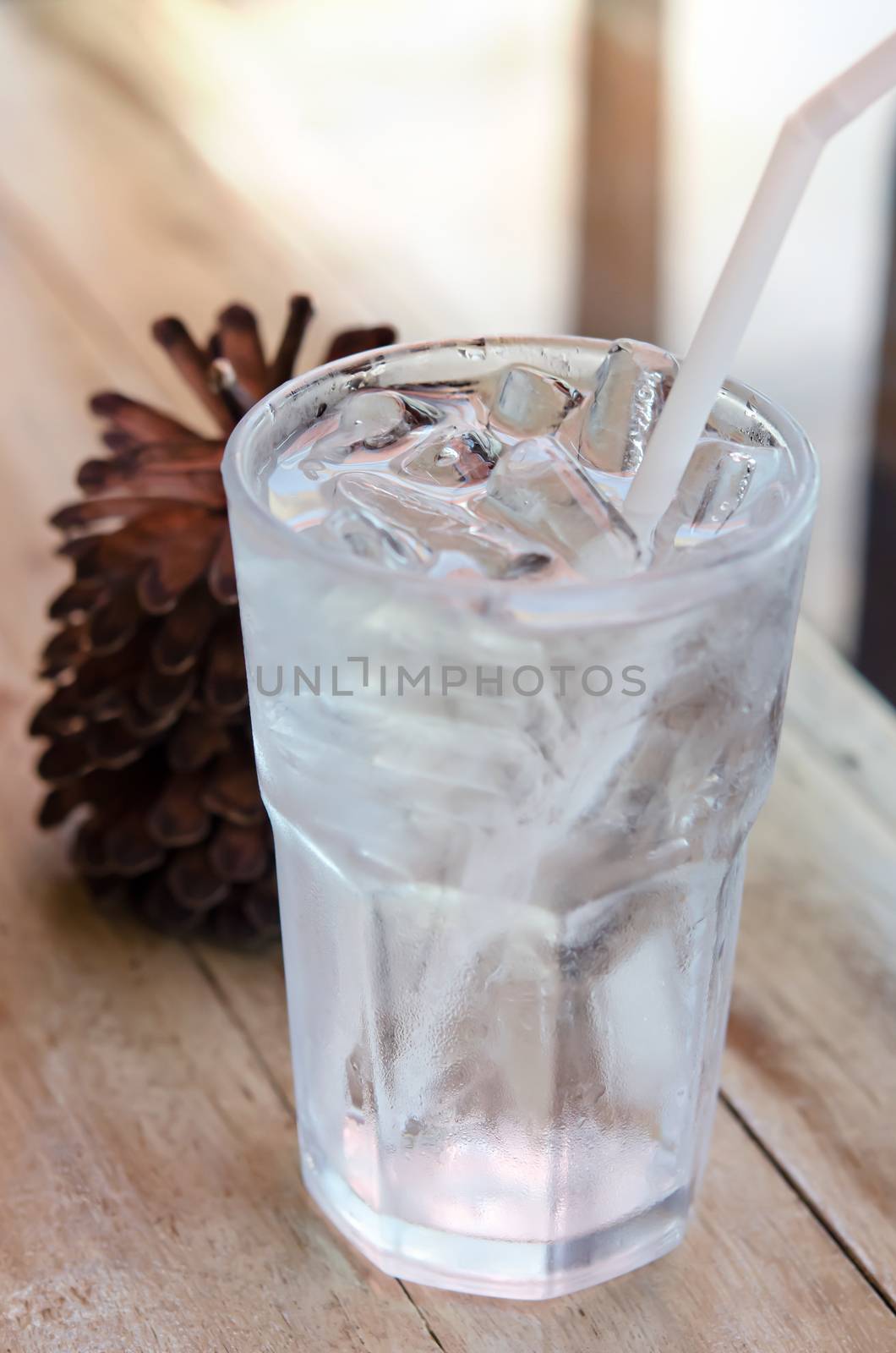 water in glass with ice  and drinking straw on table