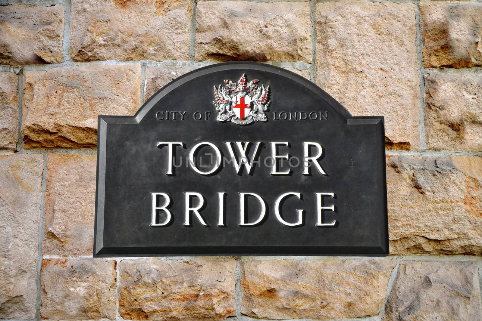 Tower Bridge sign in London in the background a sandstone wall