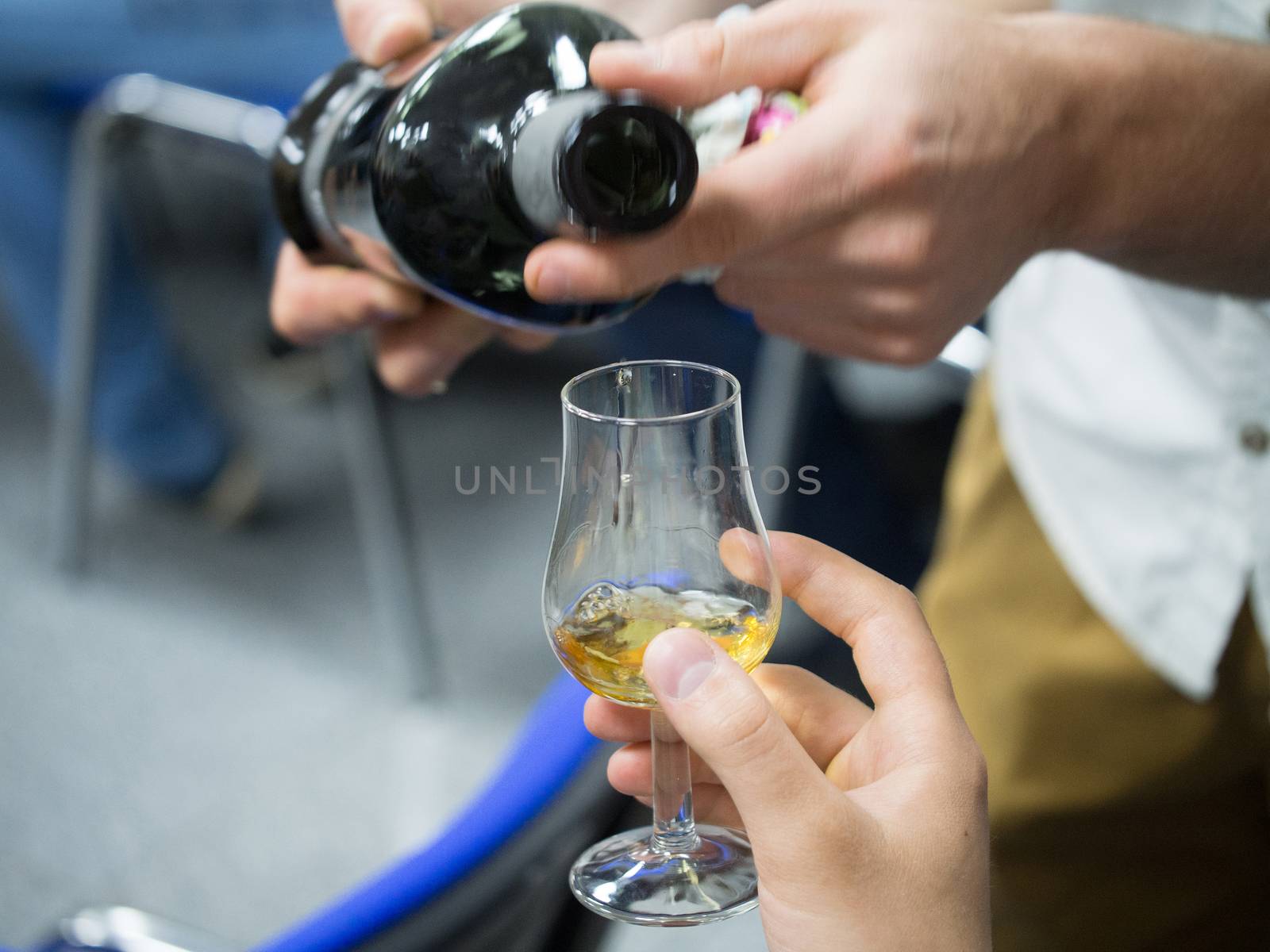Hand holding a snifter glass filled with whisky, whisky tasting event