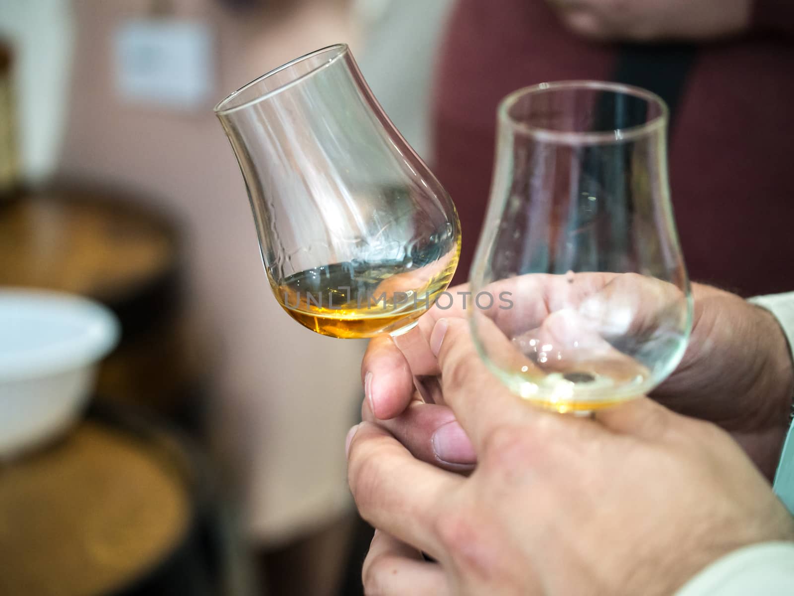 Hand holding a snifter glass filled with whisky, whisky tasting event