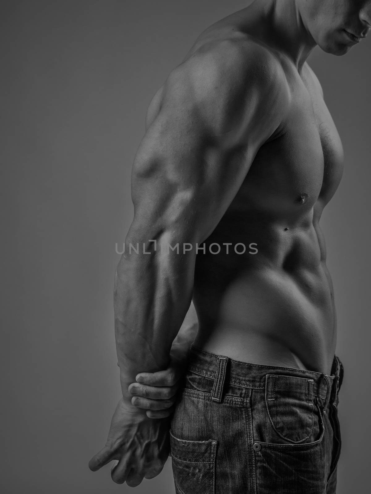 Side view of a muscular young man posing shirtless