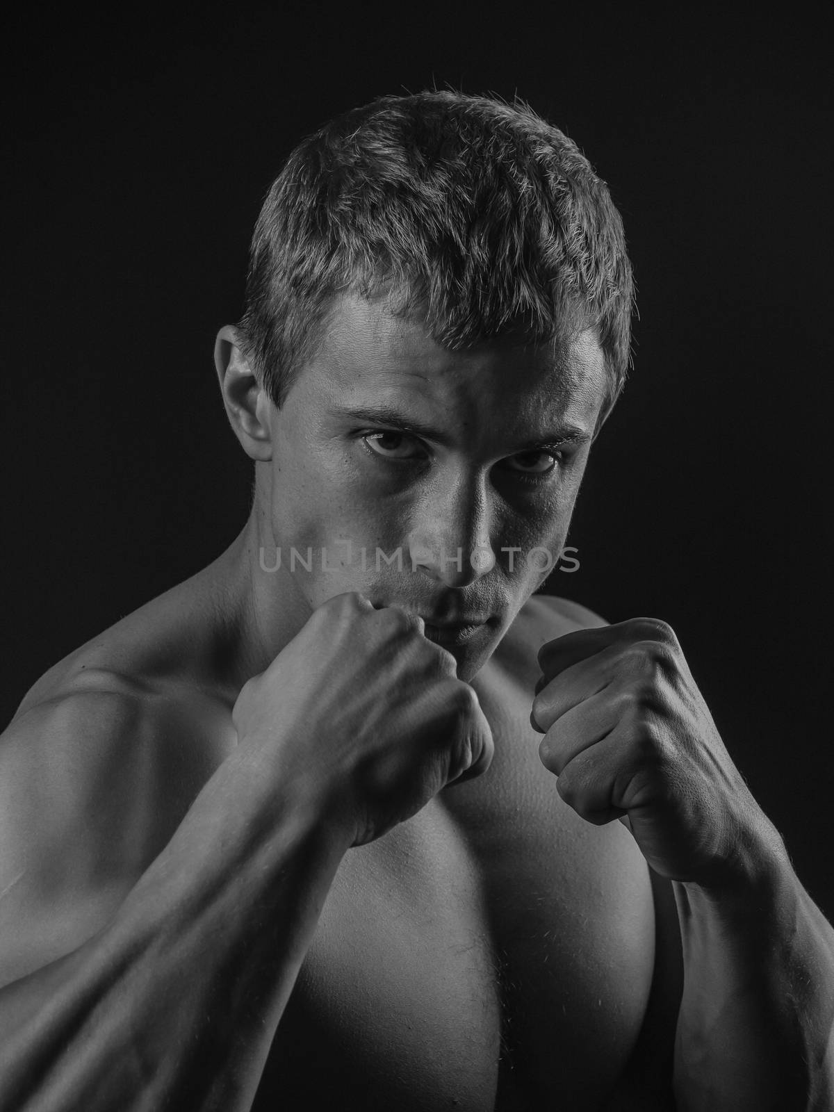 Young shirtless fit fighter doing shadow boxing