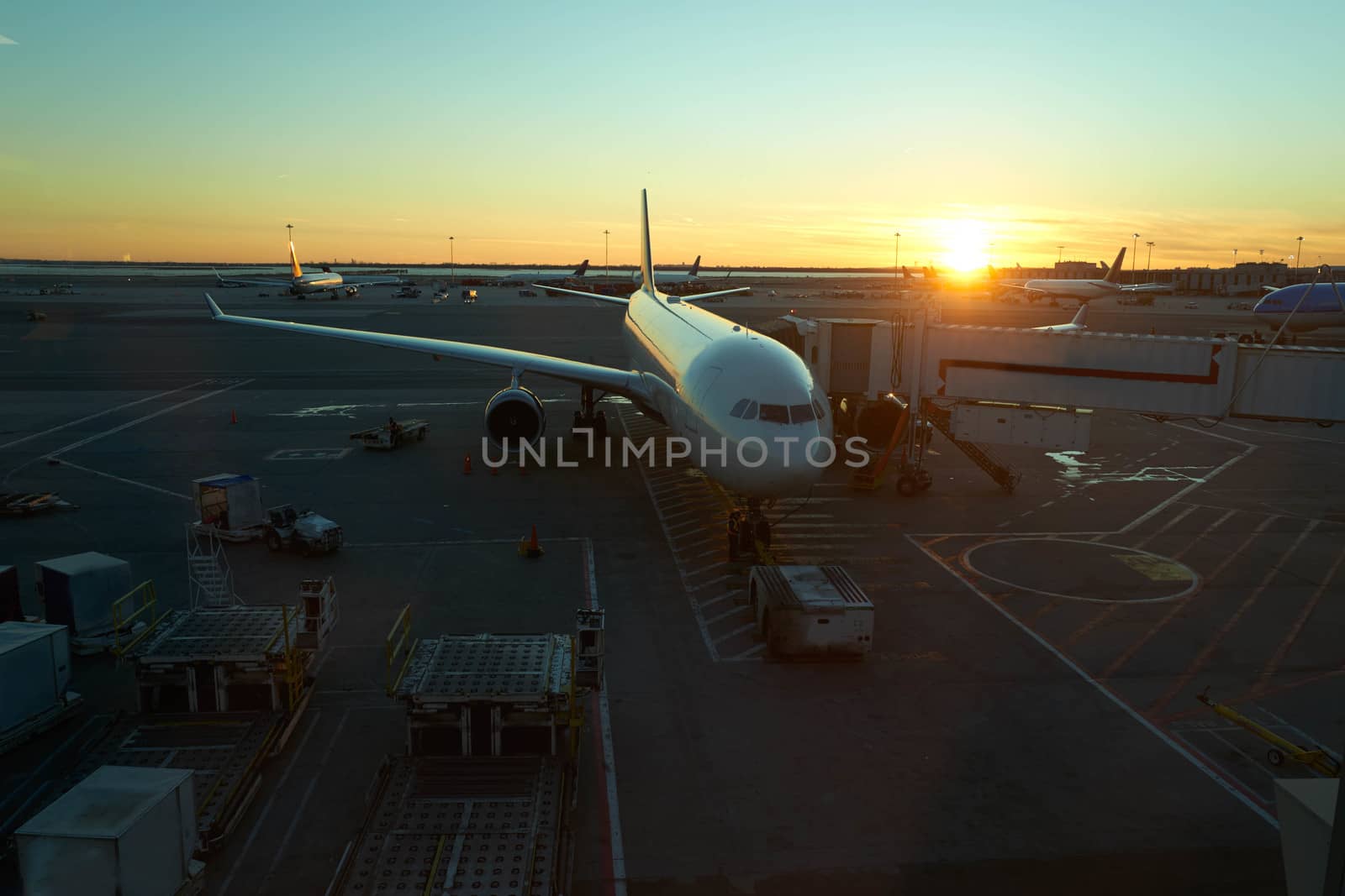 Top down view of a docked plane at airport on sunset with the golden light of the sun warming the scene.