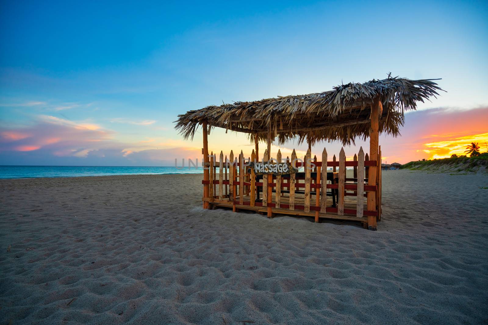 Beautiful beach of Varadero at sunset,in the middle a wooden and straw awning for massages on the beach, Varadero Cuba.