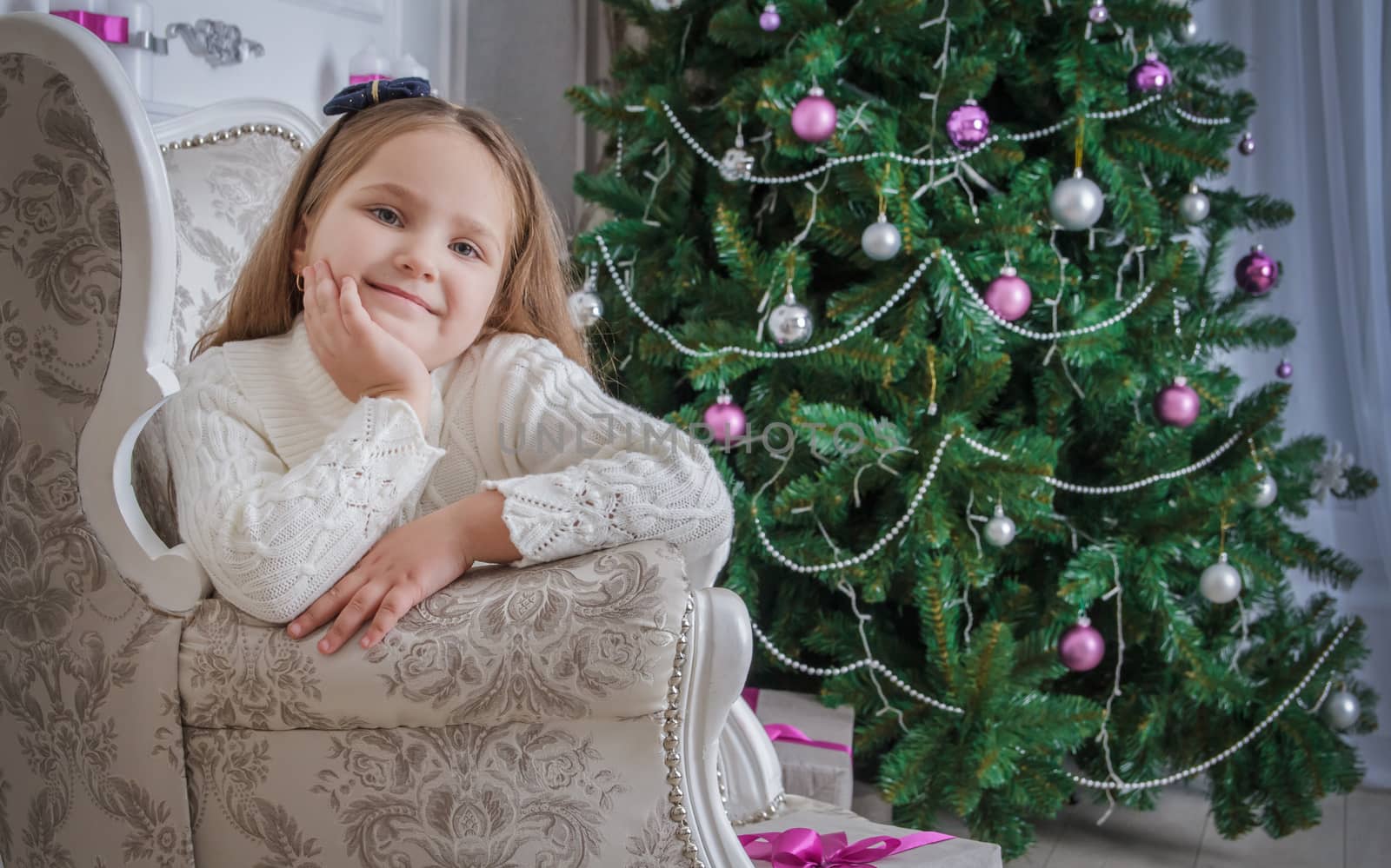 Smiling little girl near christmas tree sitting in armchair by Angel_a