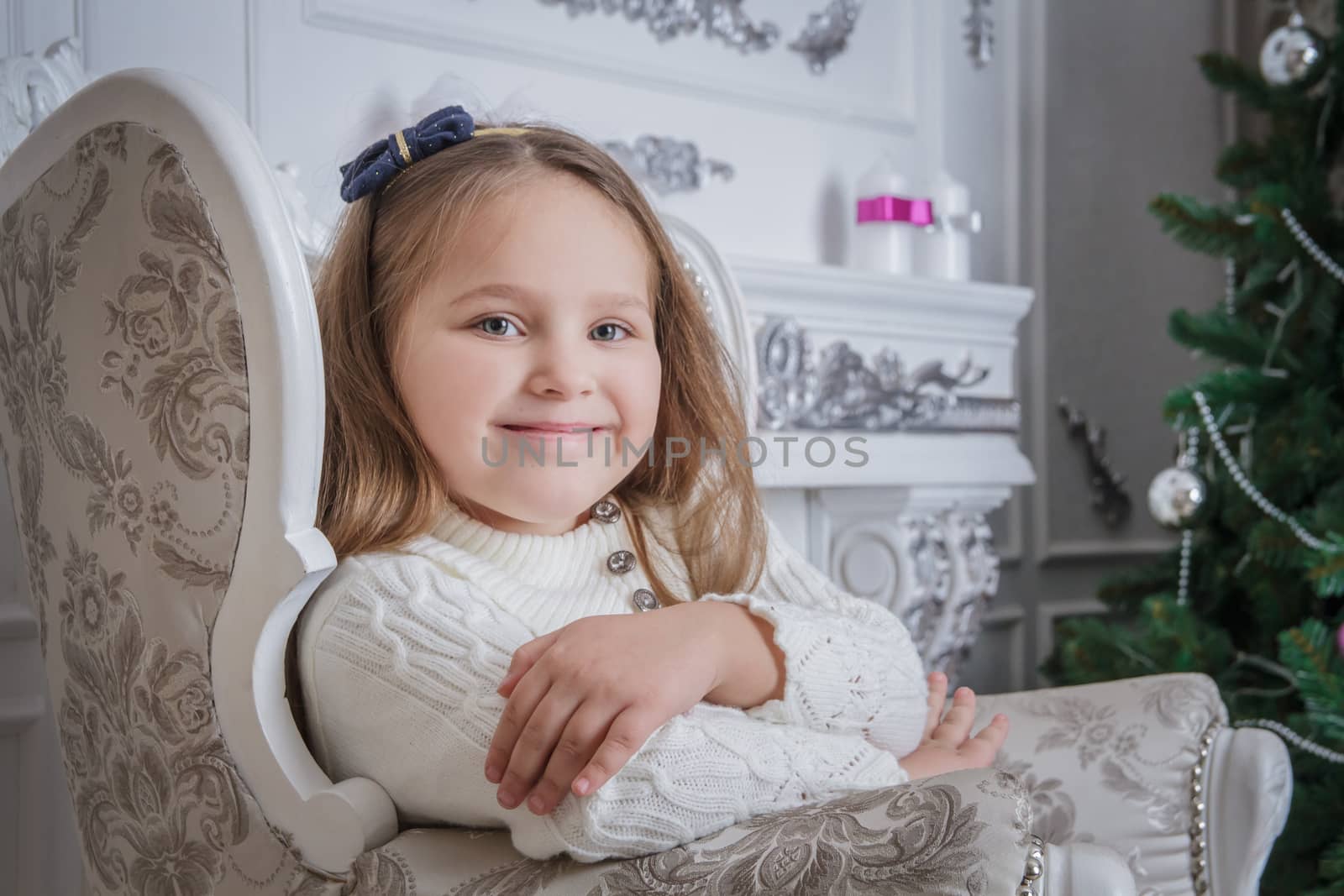 Little girl near Christmas tree sitting on armchair by Angel_a