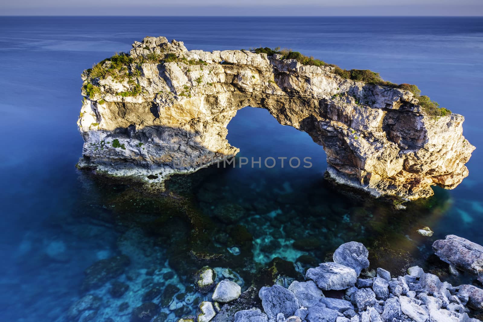 A rocky arch in the clear, blue sea water of Mallorca