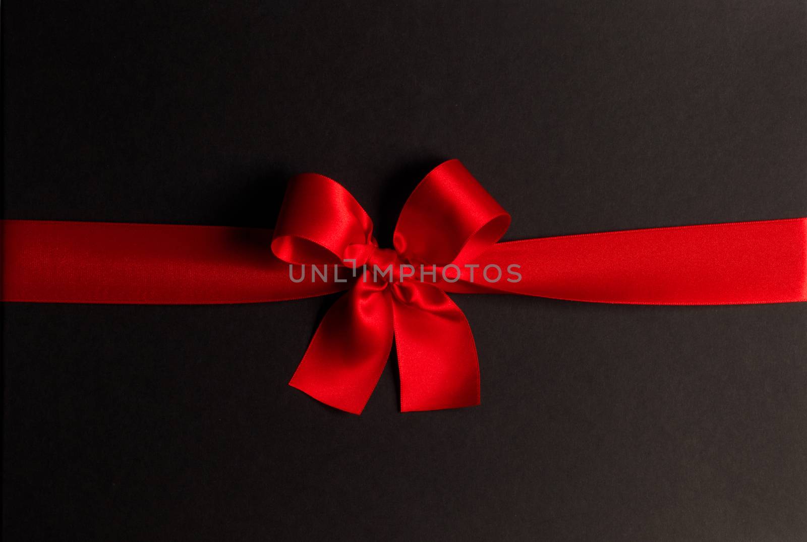 Red gift bow on black background