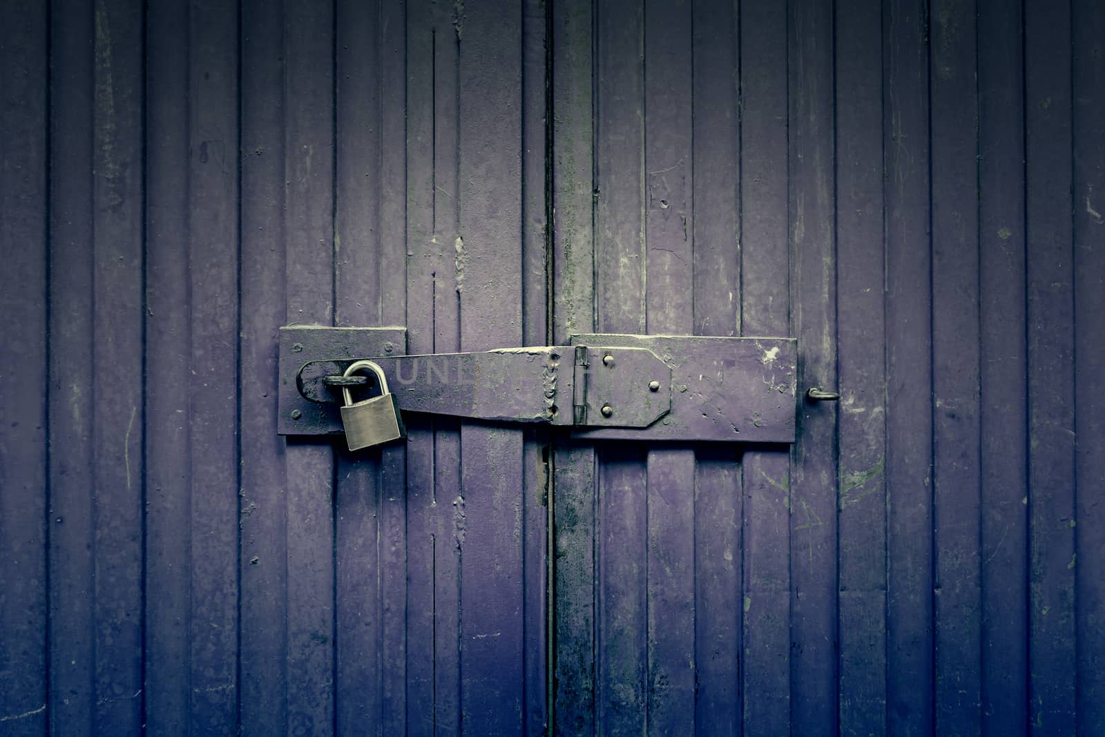 Blue door padlocked, detail of an old door painted blue, safety and security