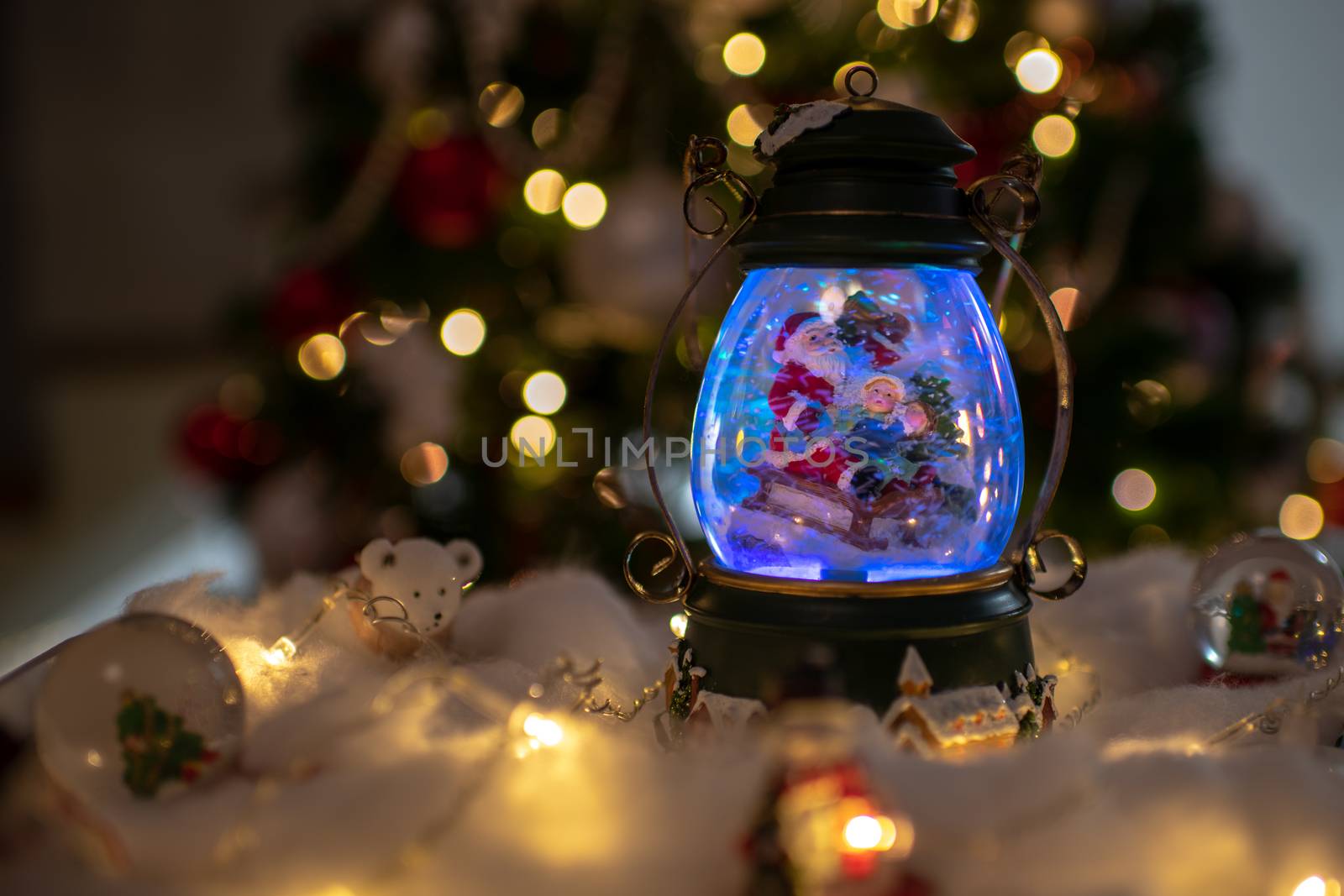 Christmas decoration, snow dome, globe with table decoration, Santaclaus on sleigh with child in winter scene, christmas tree with lights in background, selective focus