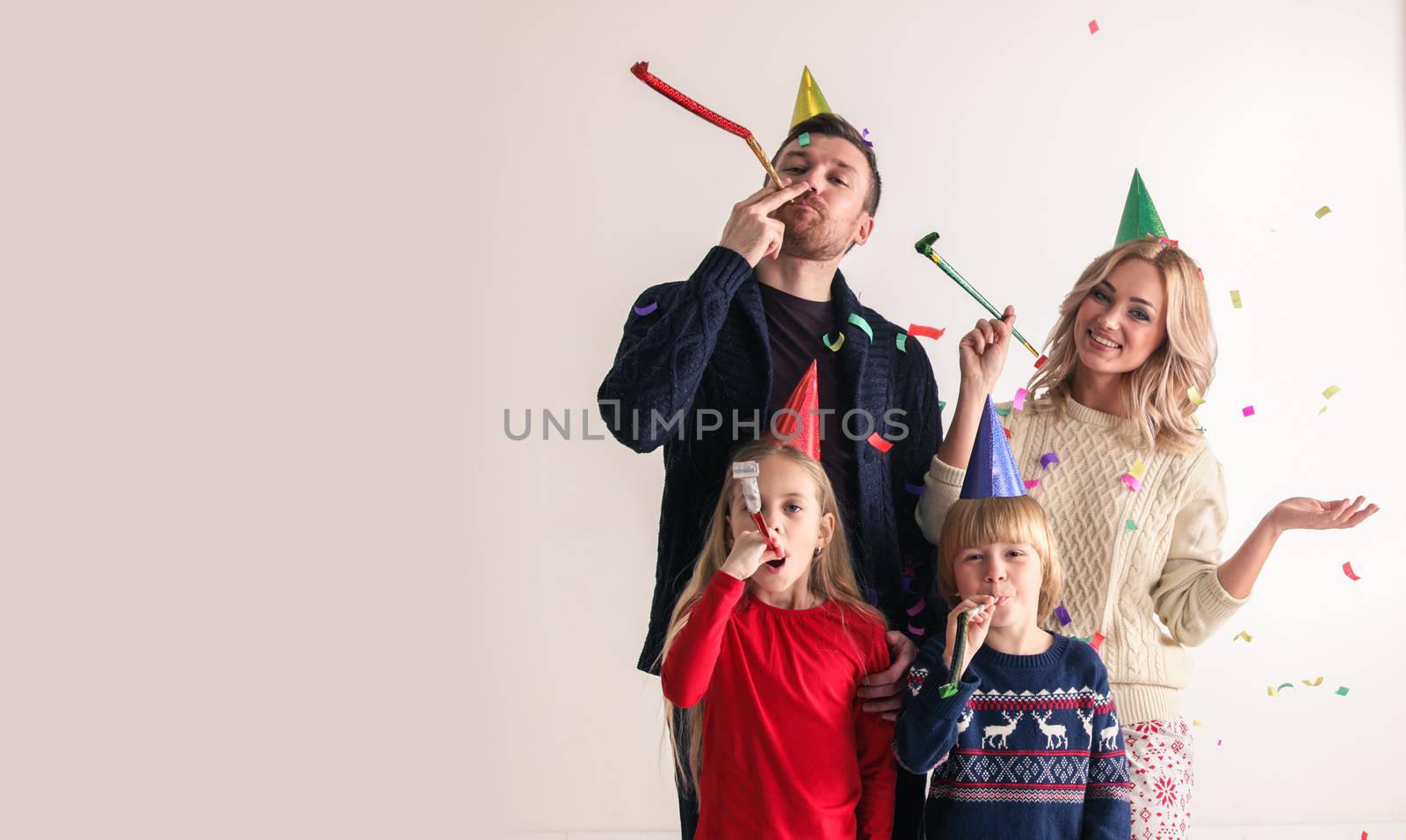 Family blowing party trumpets with confetti celebrating new year