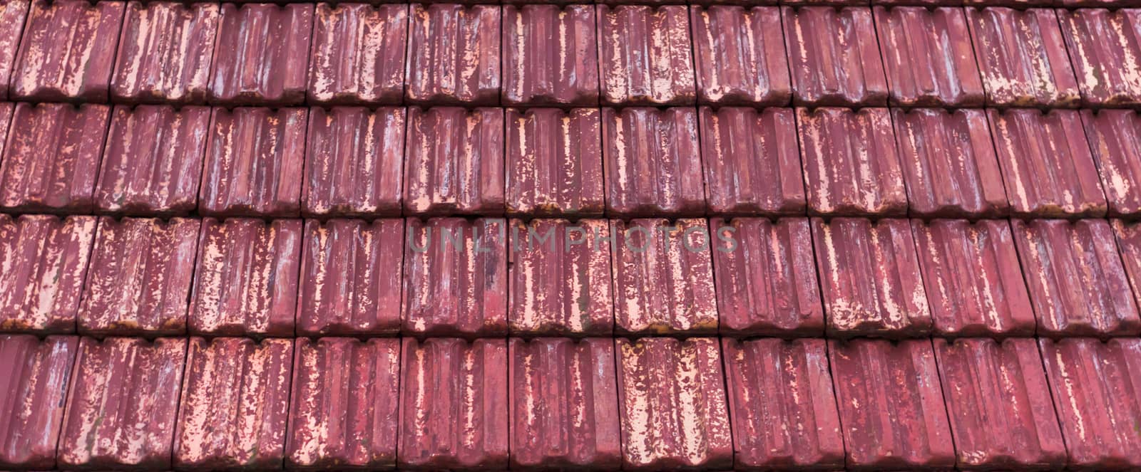 weathered and old red colored classic stone roof tiling with faded out colors, architecture pattern background