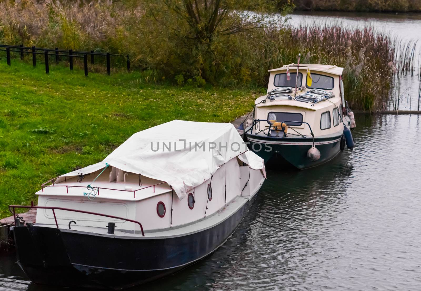 two typical dutch boats docked on the water shore, one covered u by charlottebleijenberg