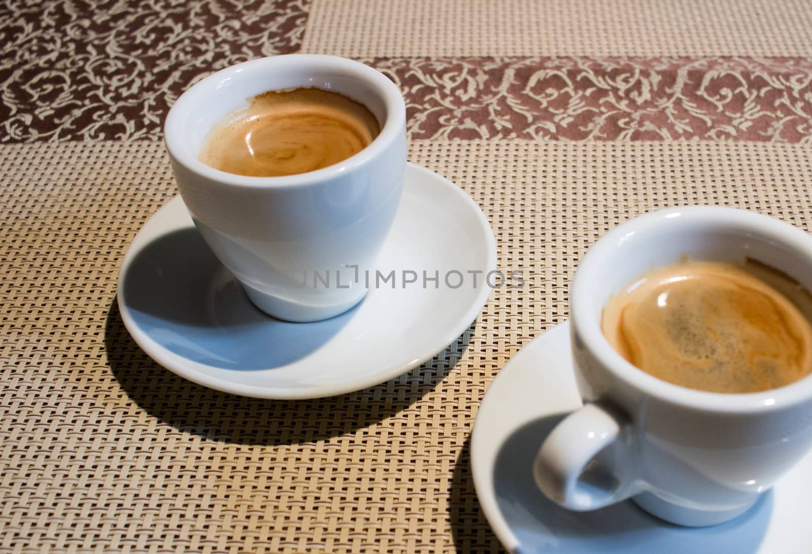 Composition of two cups of coffee on white serving plates with small metal spoons