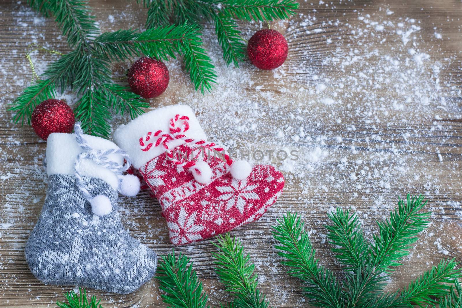 Christmas and New Year winter holiday snowbound composition of stockings on wooden space background with green fir tree branches and balls ornament