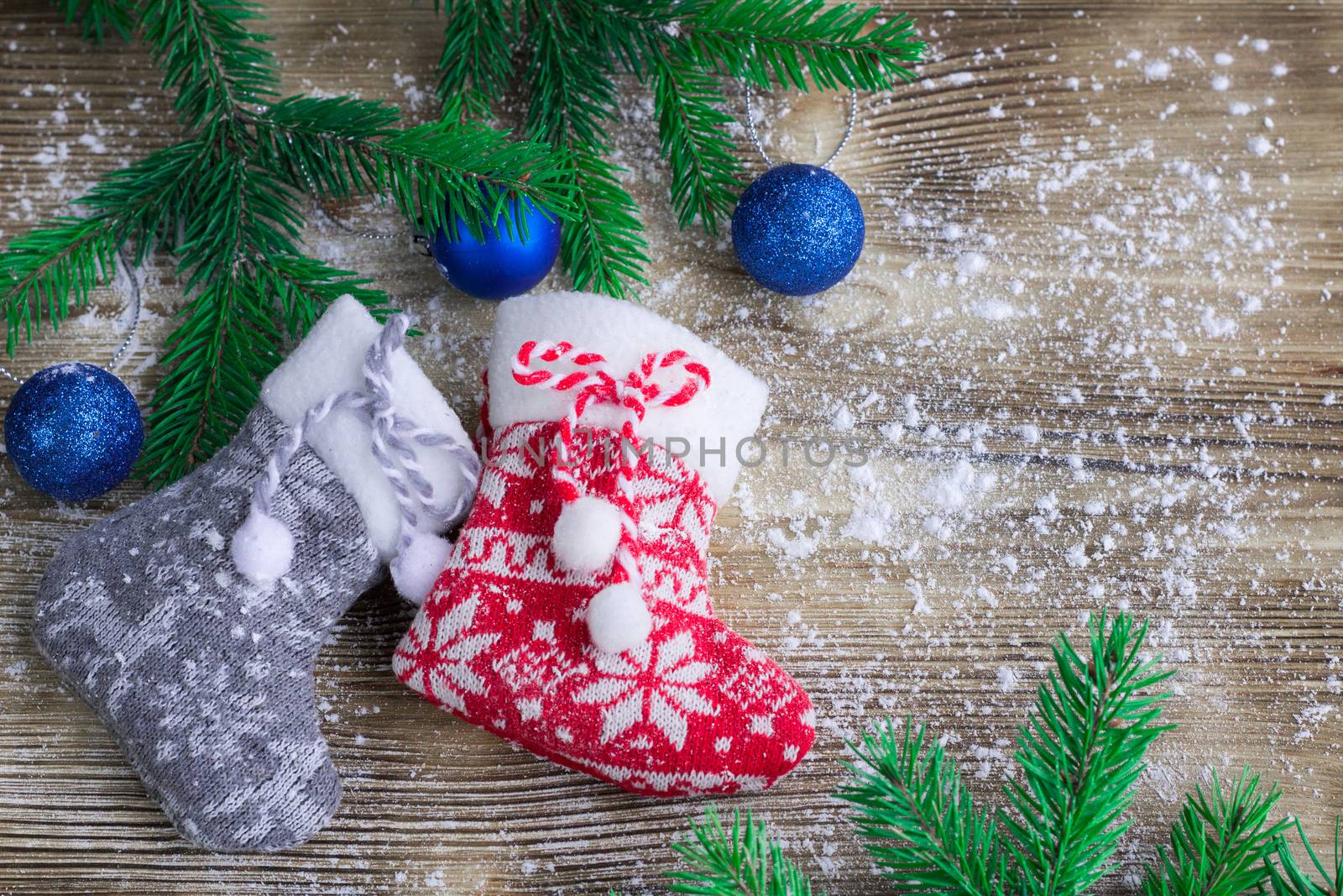 Christmas and New Year winter holiday snowbound composition of stockings on wooden space background with green fir tree branches and balls ornament