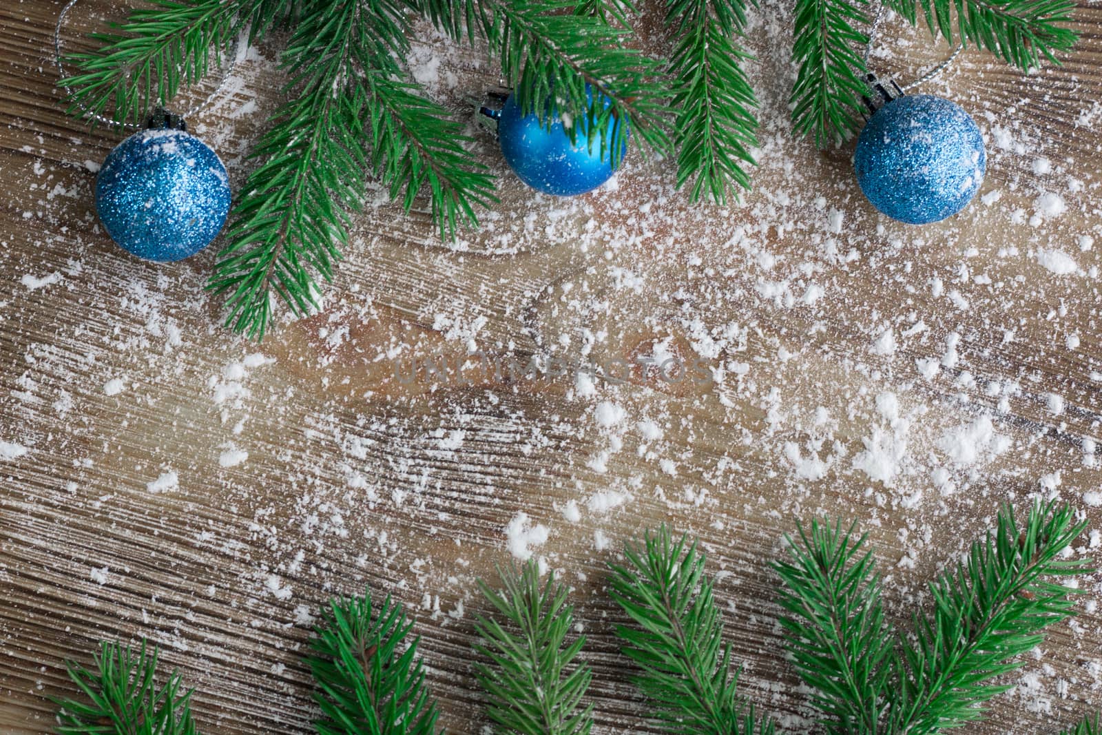 Christmas and New Year winter holiday snowbound wooden space background with green fir tree branches and blue ball ornament