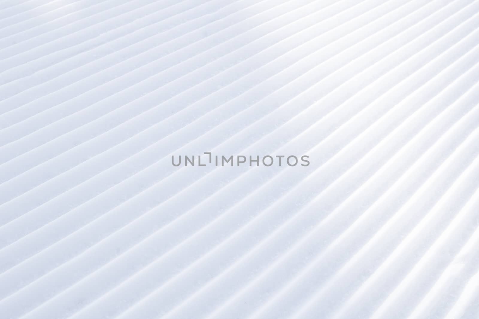 Background of diagonal geometrical parallel stripes of snow with light shadow