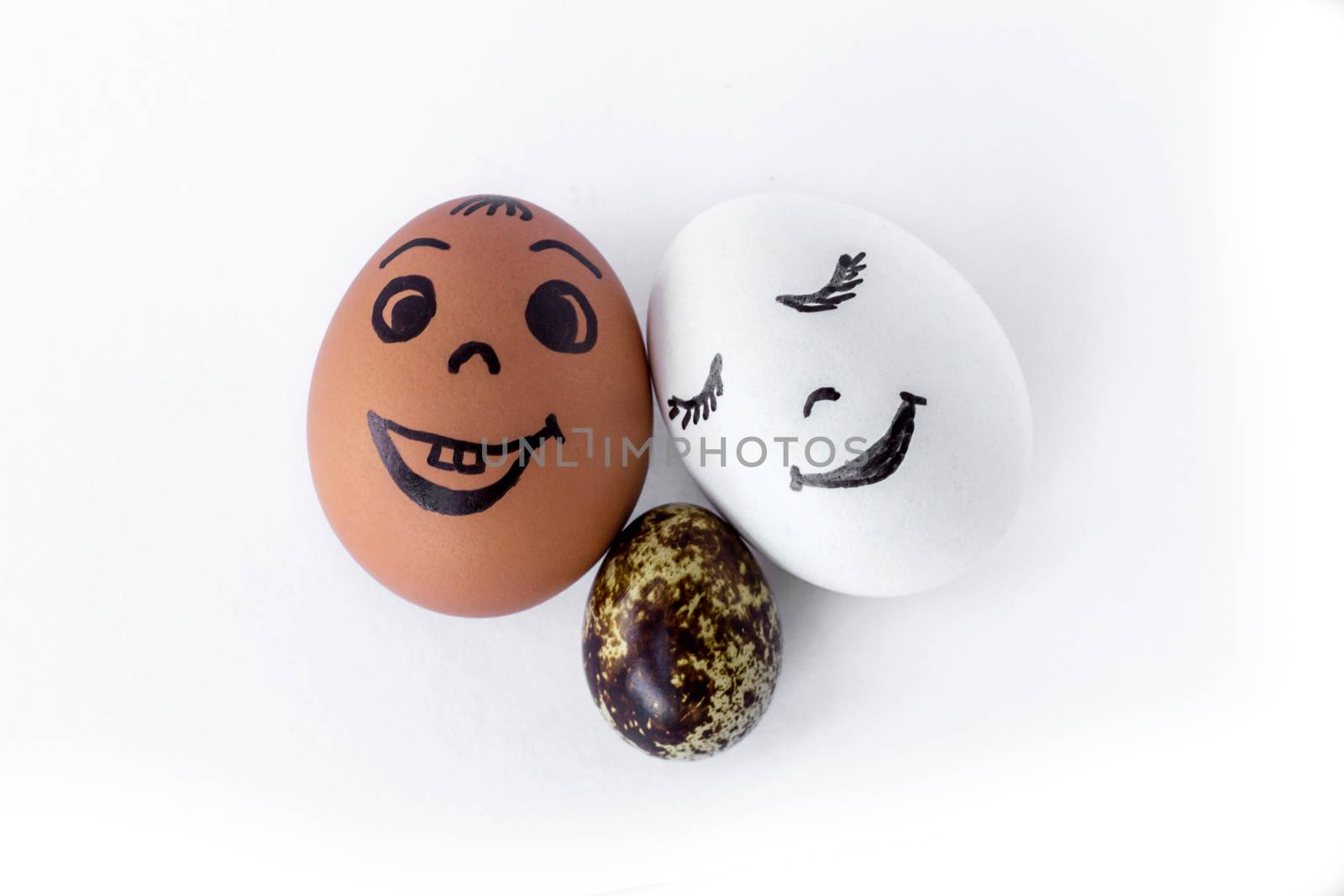 Funny eggs imitating a happy mixed family with versicolored baby on white background