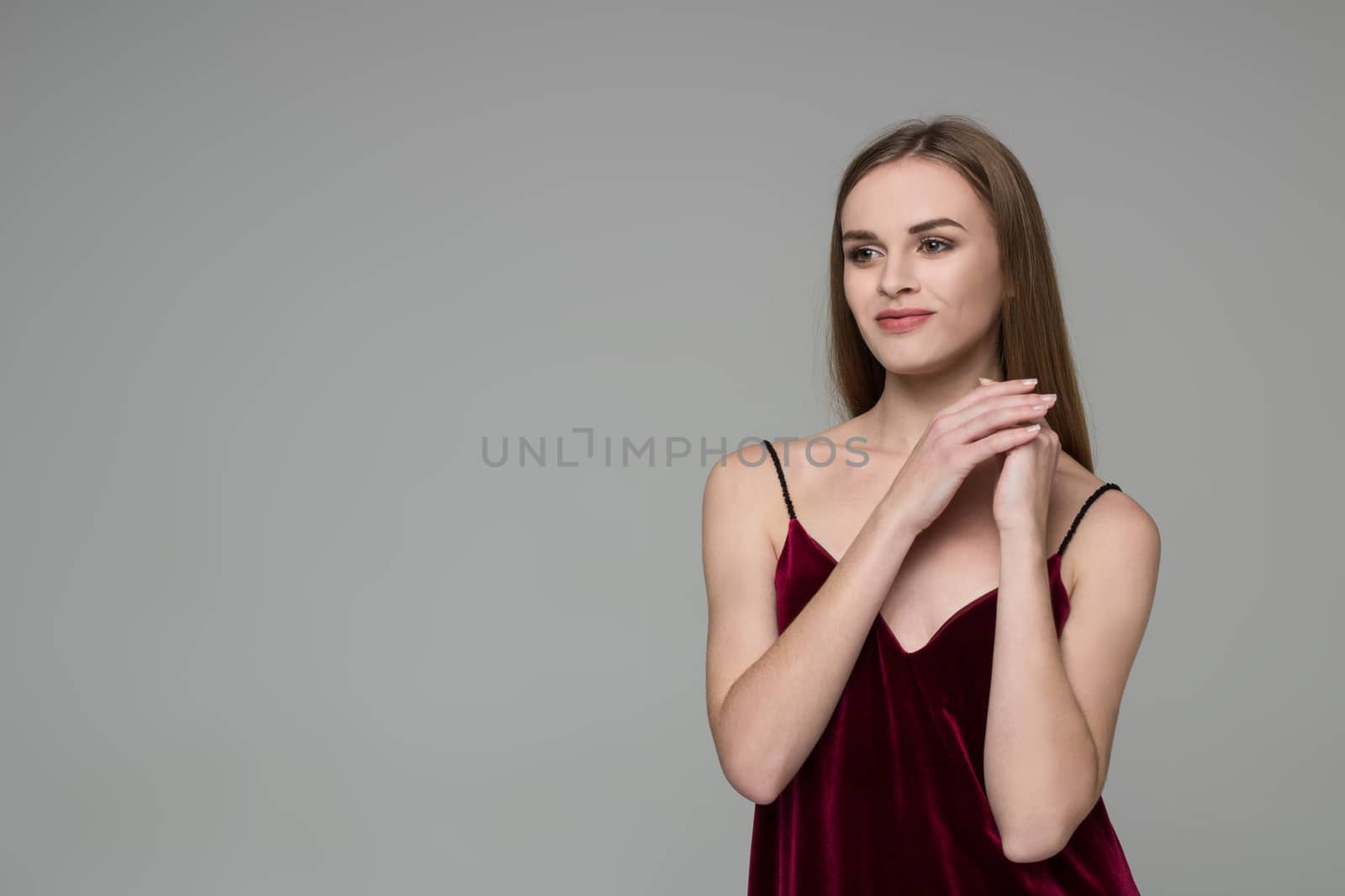 Portrait of posing young model long-haired blond girl in dark red dress showing emotions