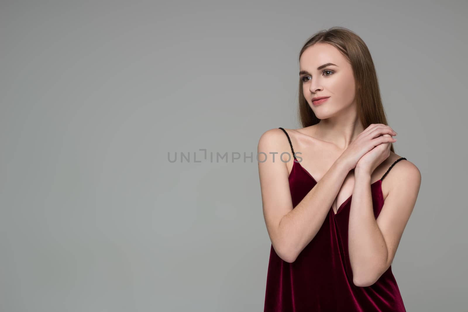 Portrait of posing young model long-haired blond girl in dark red dress showing emotions